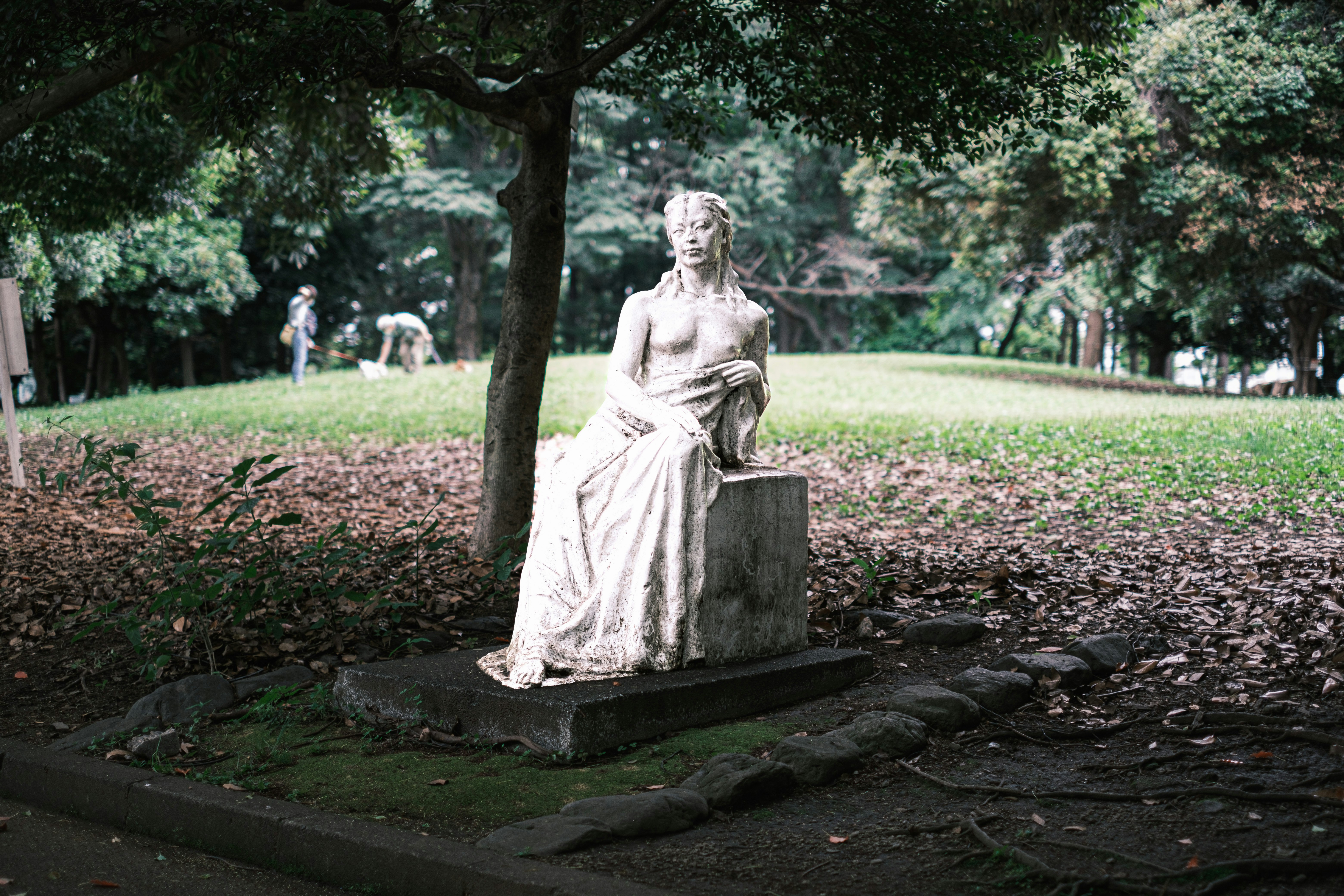stone pedestal statue sitting in a park