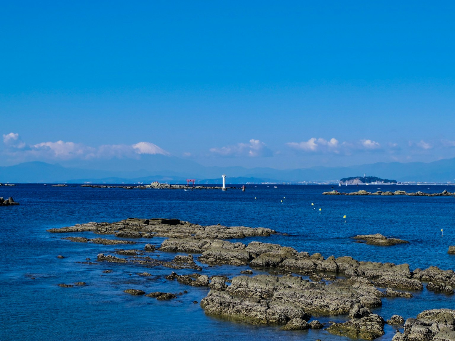Vista escénica del océano azul y la costa rocosa con un faro blanco
