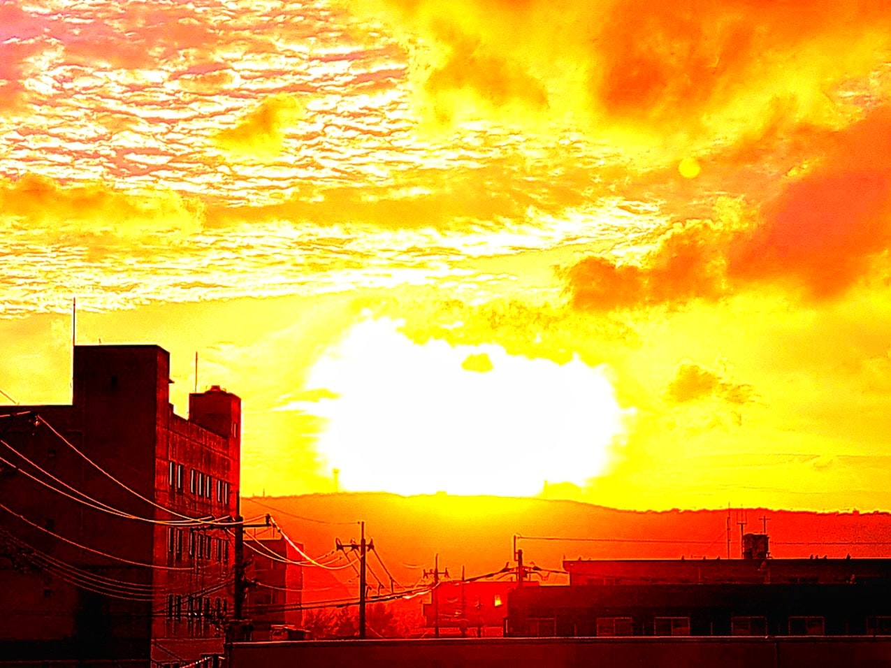 夕日と夕焼けの空に広がる雲と街並みのシルエット