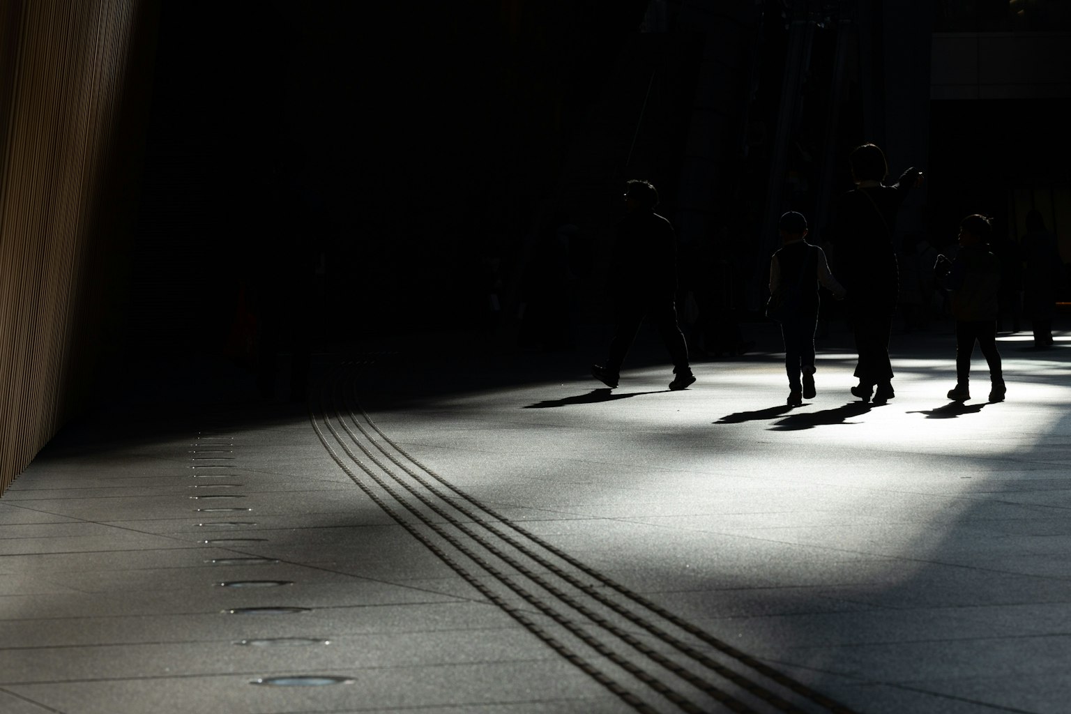 Siluetas de personas caminando en sombras con contraste de luz