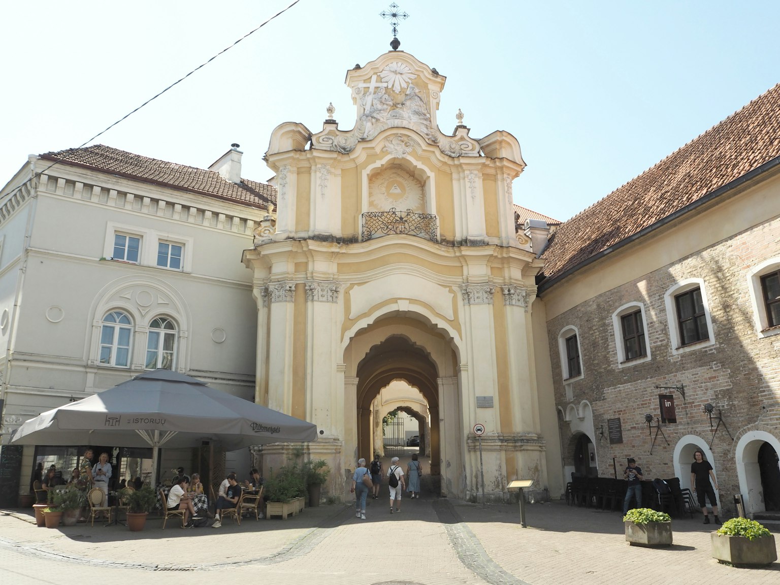 Historisches Gebäude mit Torbogen und Außencafé auf einem Platz