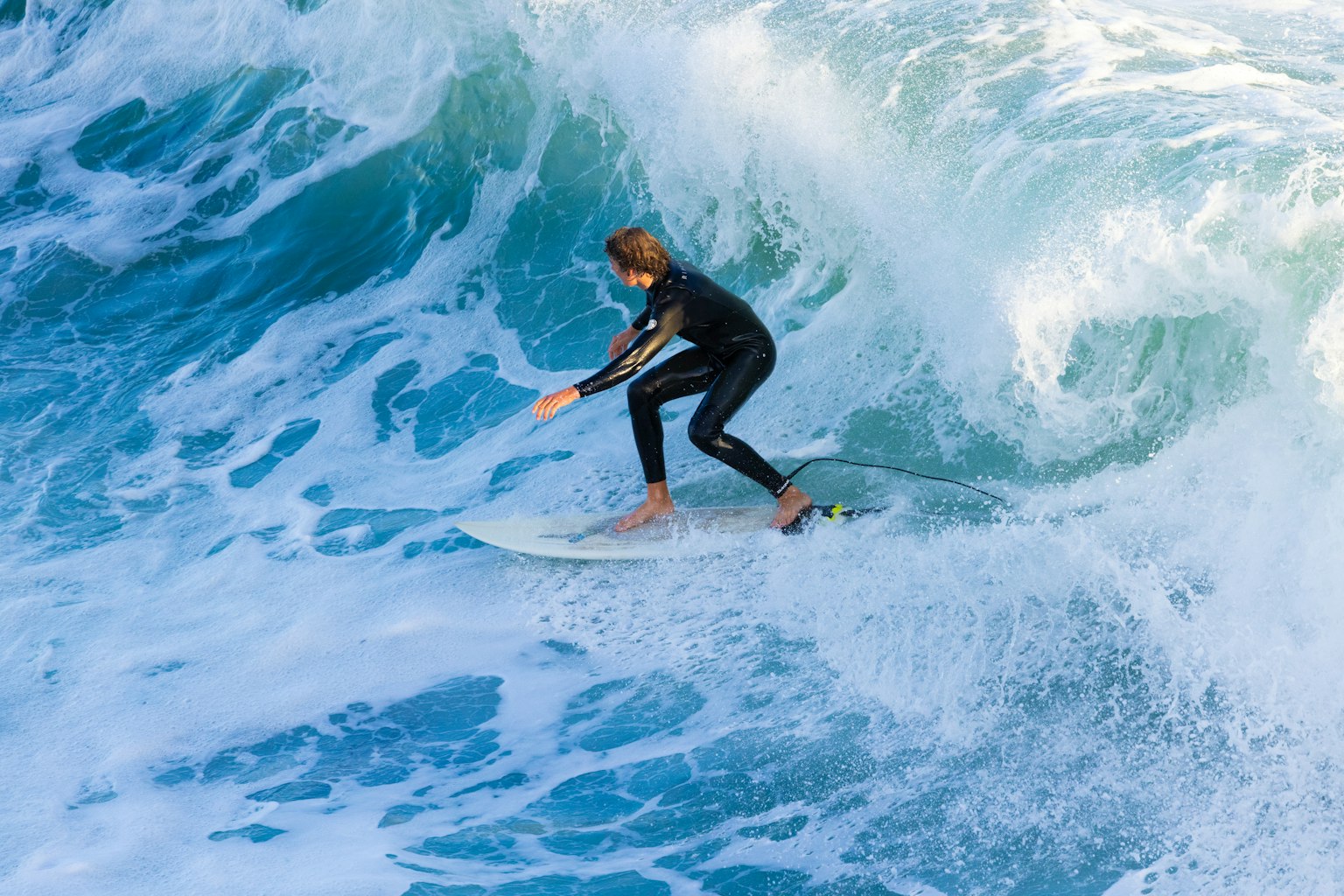 Ein männlicher Surfer, der auf einer Welle mit seinem Surfbrett balanciert