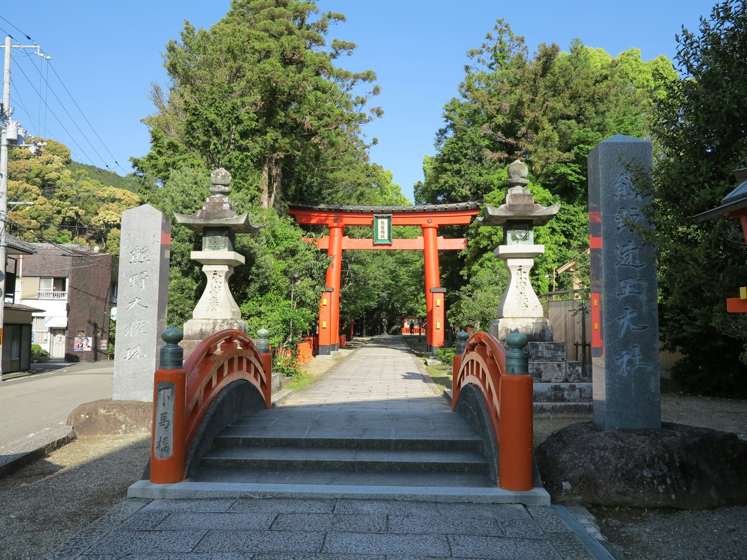 Vista panoramica di un santuario shintoista con un torii rosso e un ponte di pietra