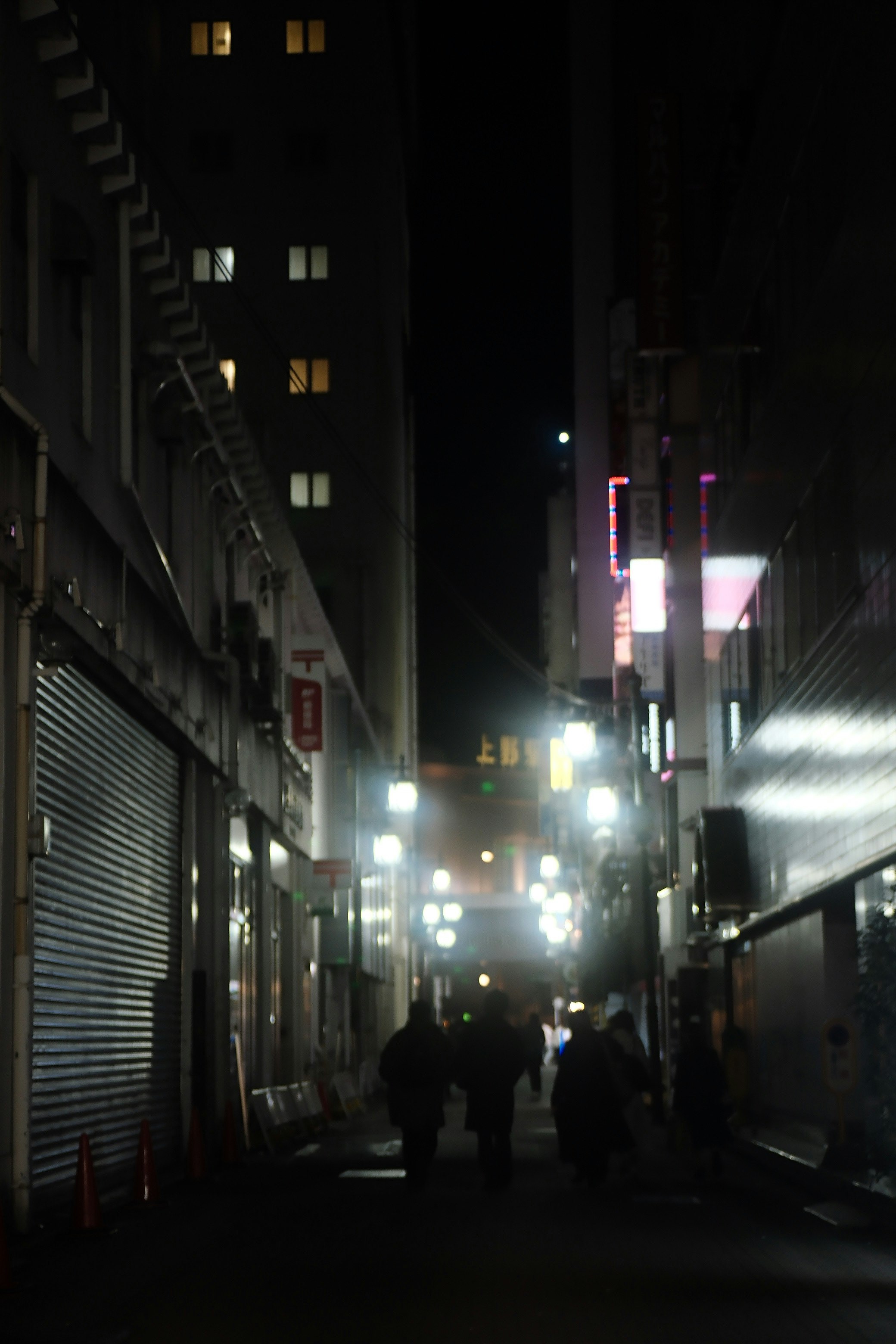 夜の街の狭い路地に立つ人々と明かり