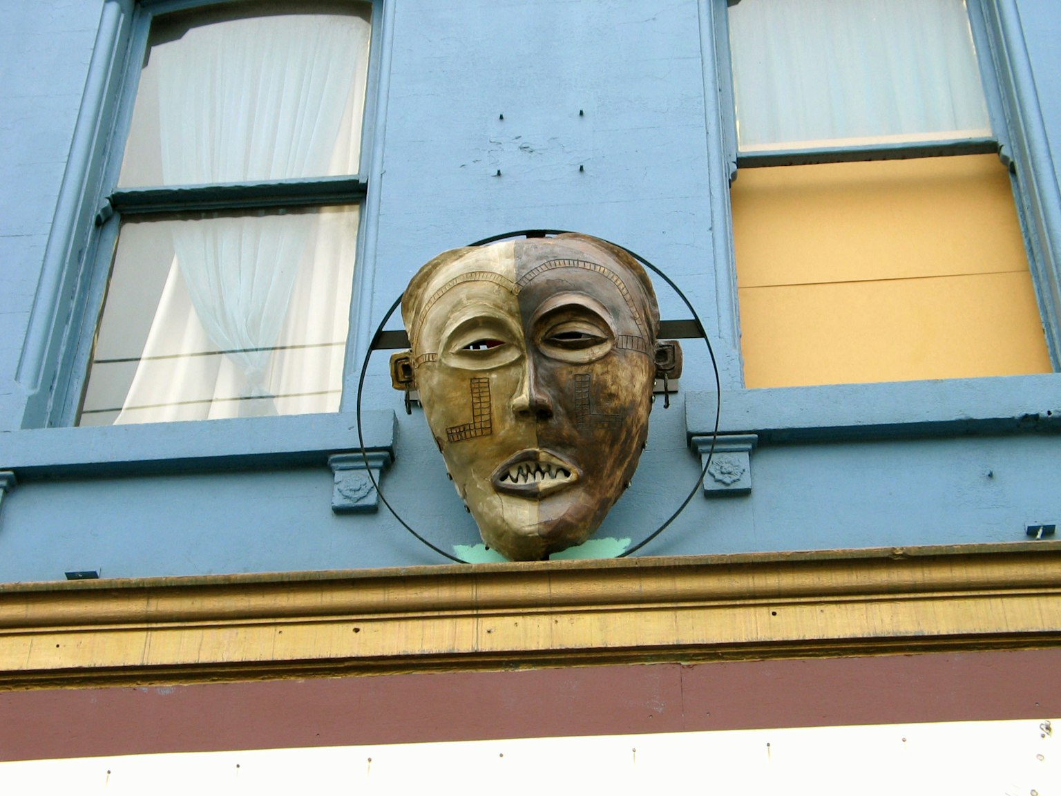 Sculpture unique de visage moitié fixée sur un mur bleu