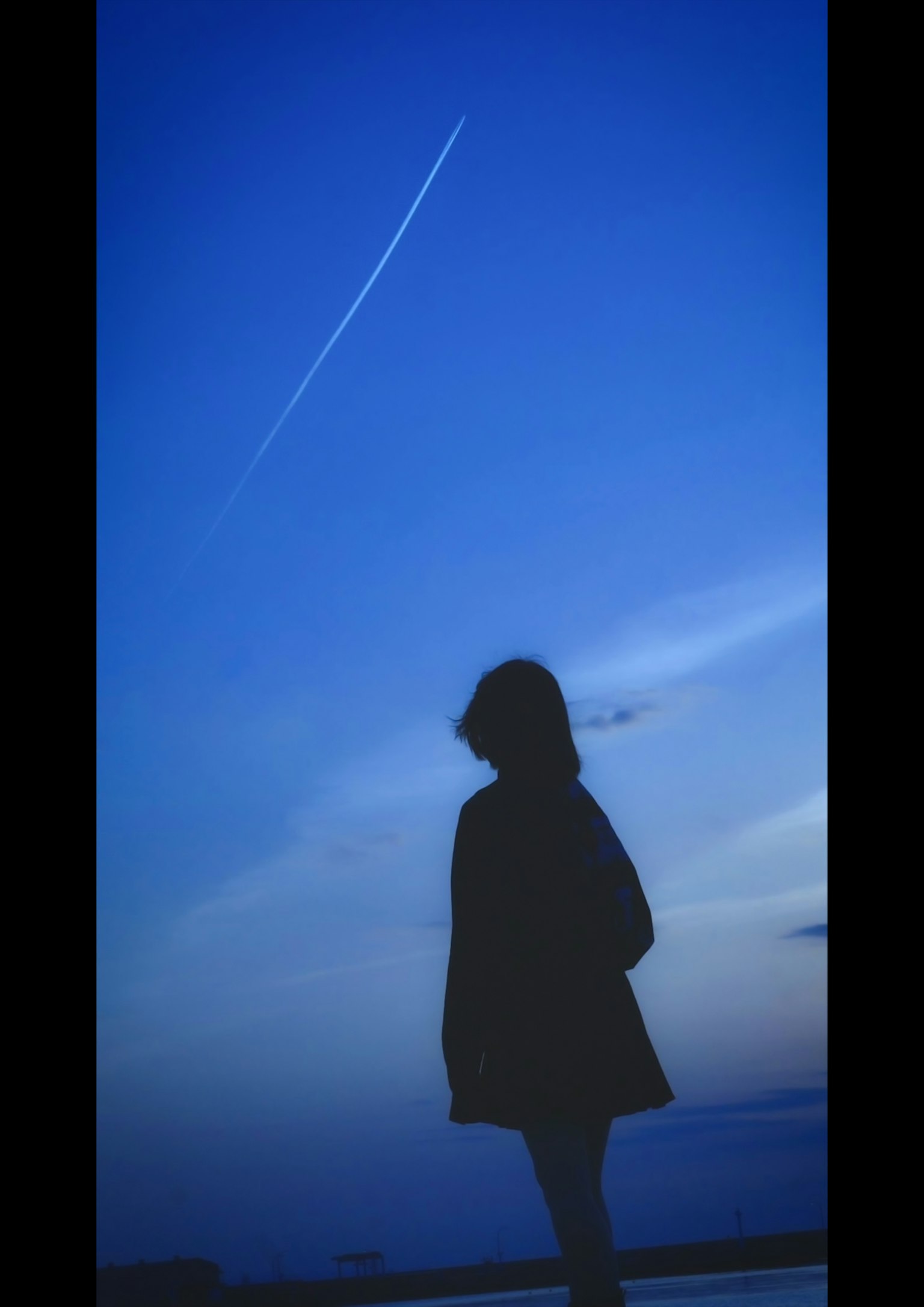 Silhouette di una donna che sta sotto un cielo blu