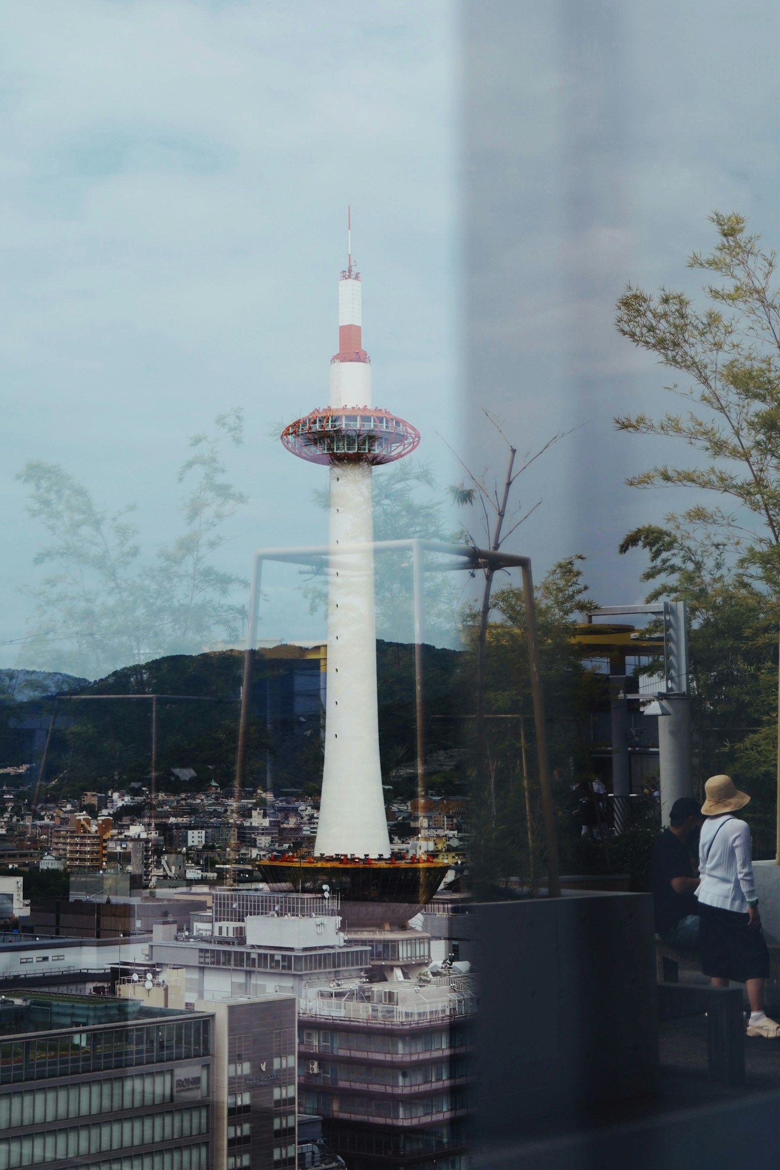Kyoto Tower reflected in a cityscape with people