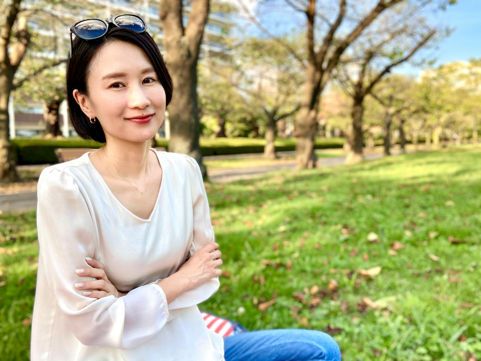 공원에서 미소 짓고 있는 여성 흰색 블라우스 착용 나무 배경