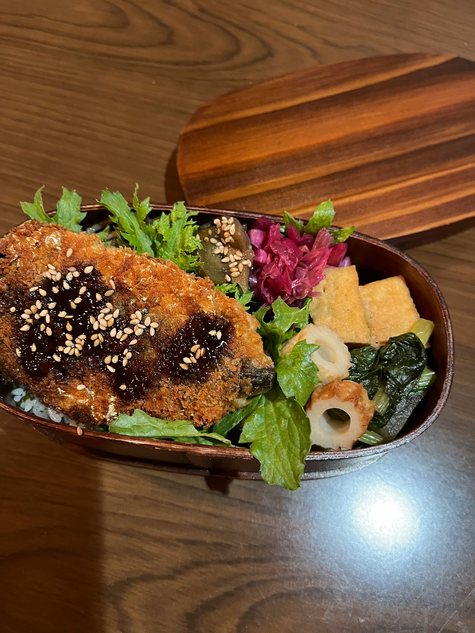 Una caja bento de madera llena de katsu crujiente y verduras coloridas