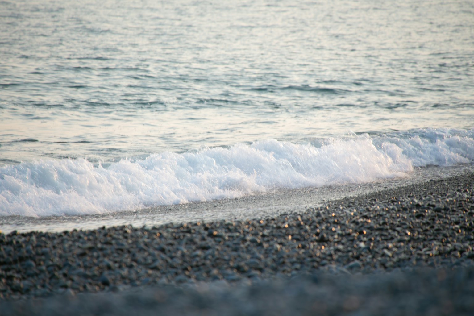平静的海浪拍打着卵石海滩