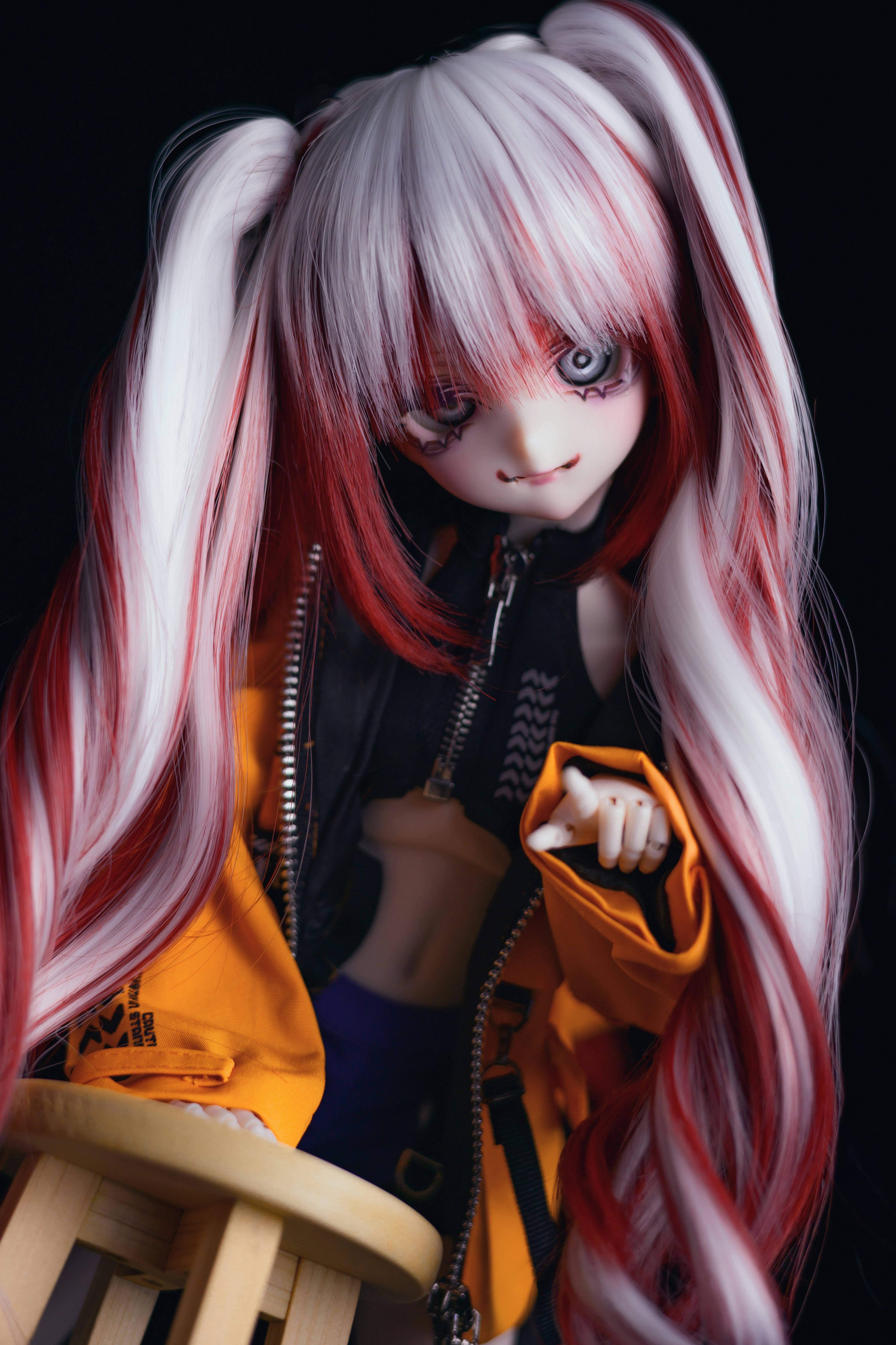portrait d’un personnage style poupée aux longs cheveux rouge et blanc tenant un petit objet