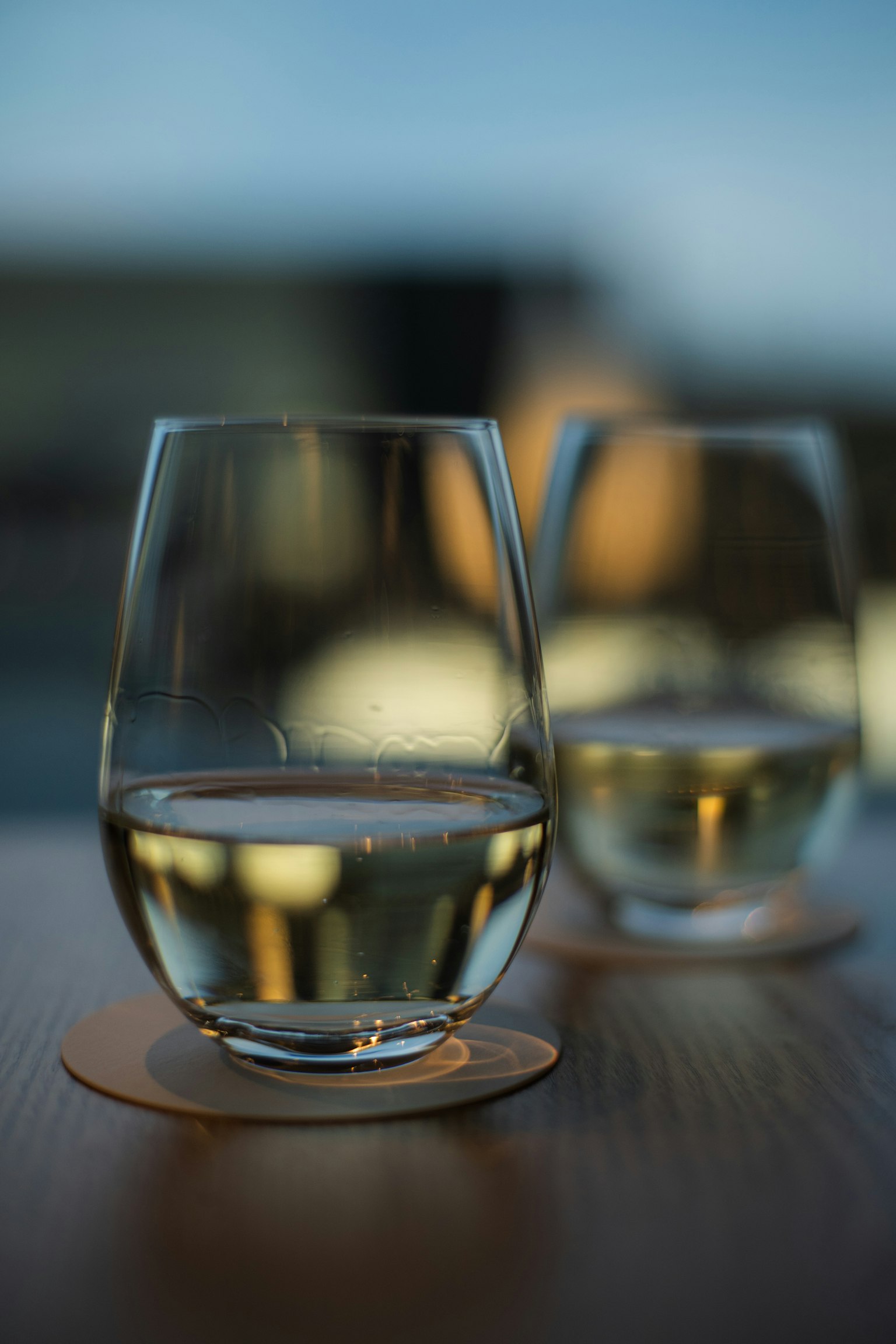 Zwei Gläser Weißwein auf einem Holztisch mit unscharfem Hintergrund