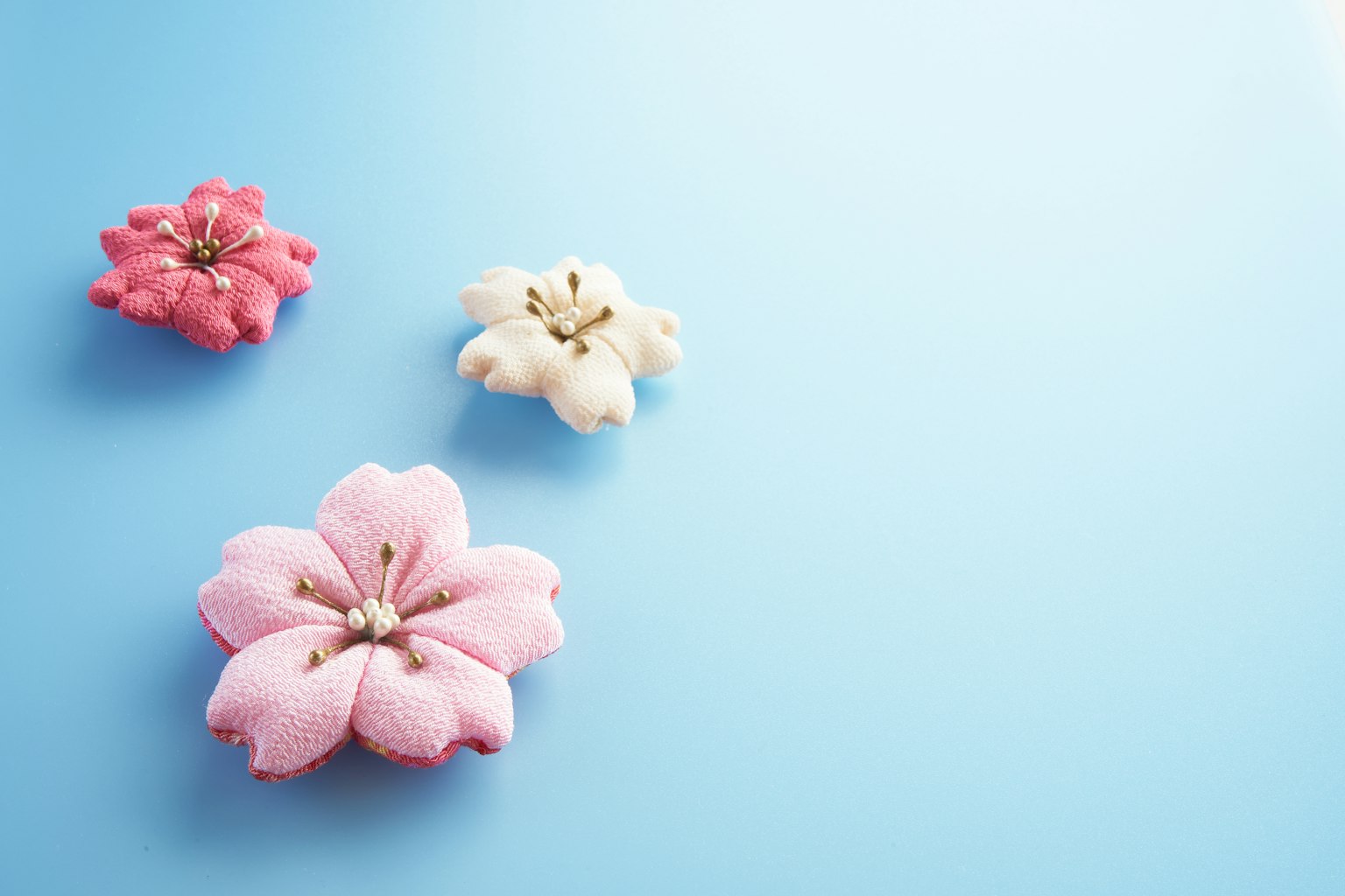Tre macarons a forma di fiore rosa e bianco su uno sfondo blu