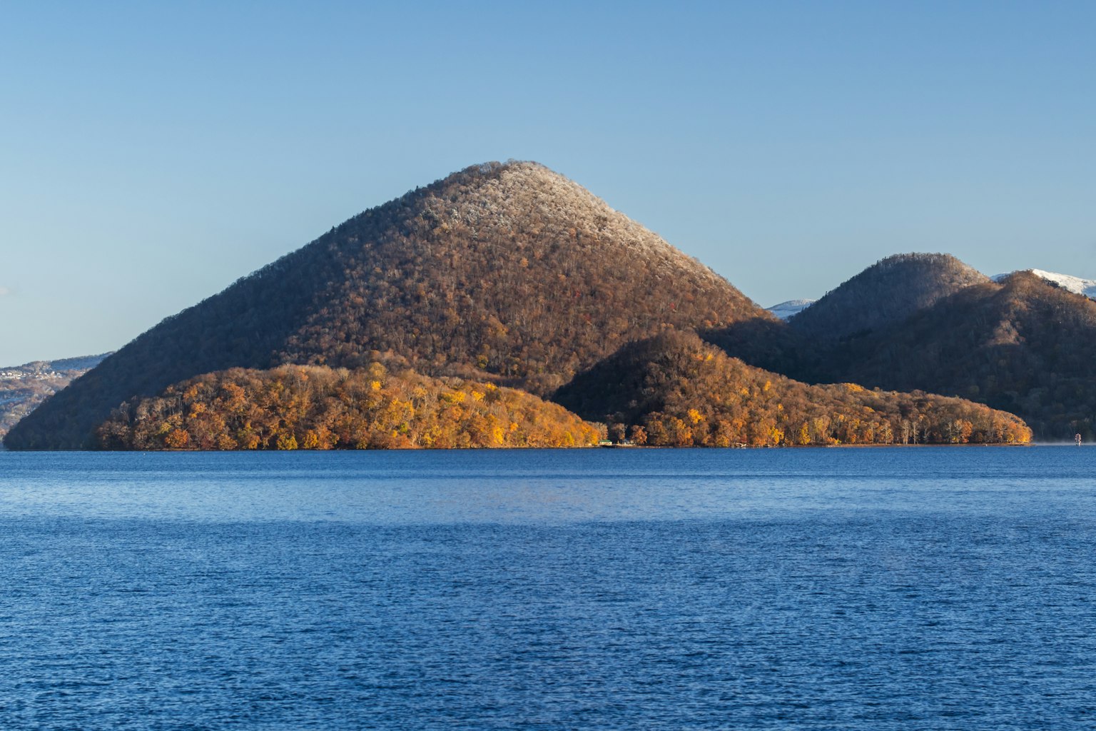 Vue panoramique de montagnes aux couleurs d'automne près d'un lac bleu avec des sommets enneigés