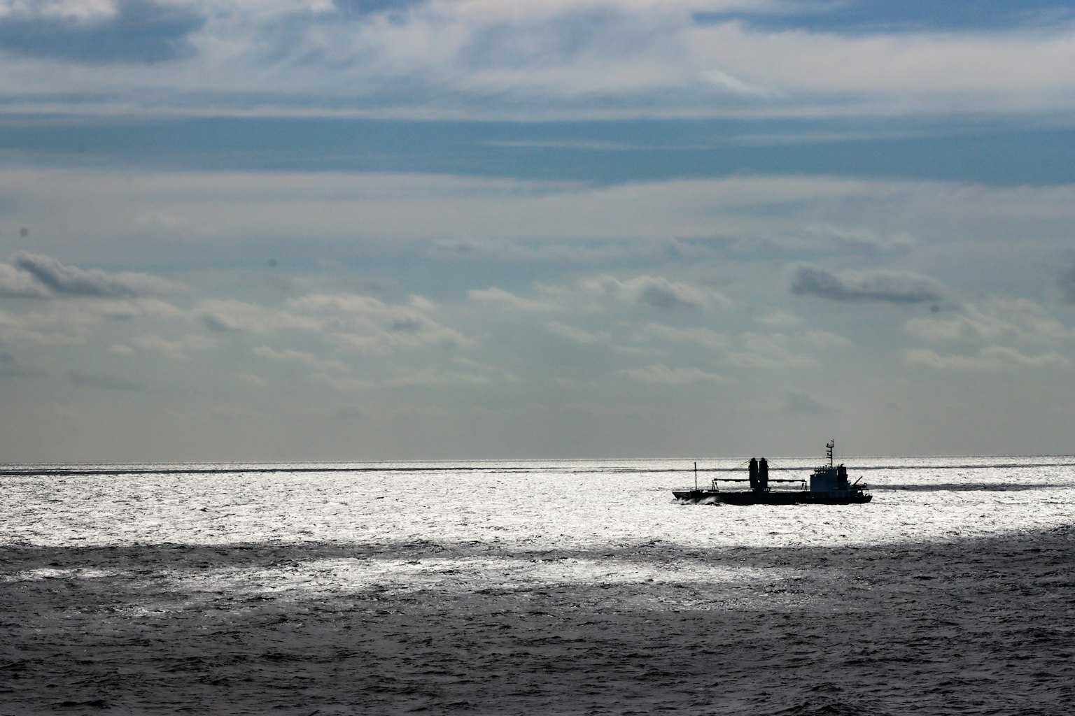 Ein Boot auf dem schimmernden Meer unter einem bewölkten Himmel