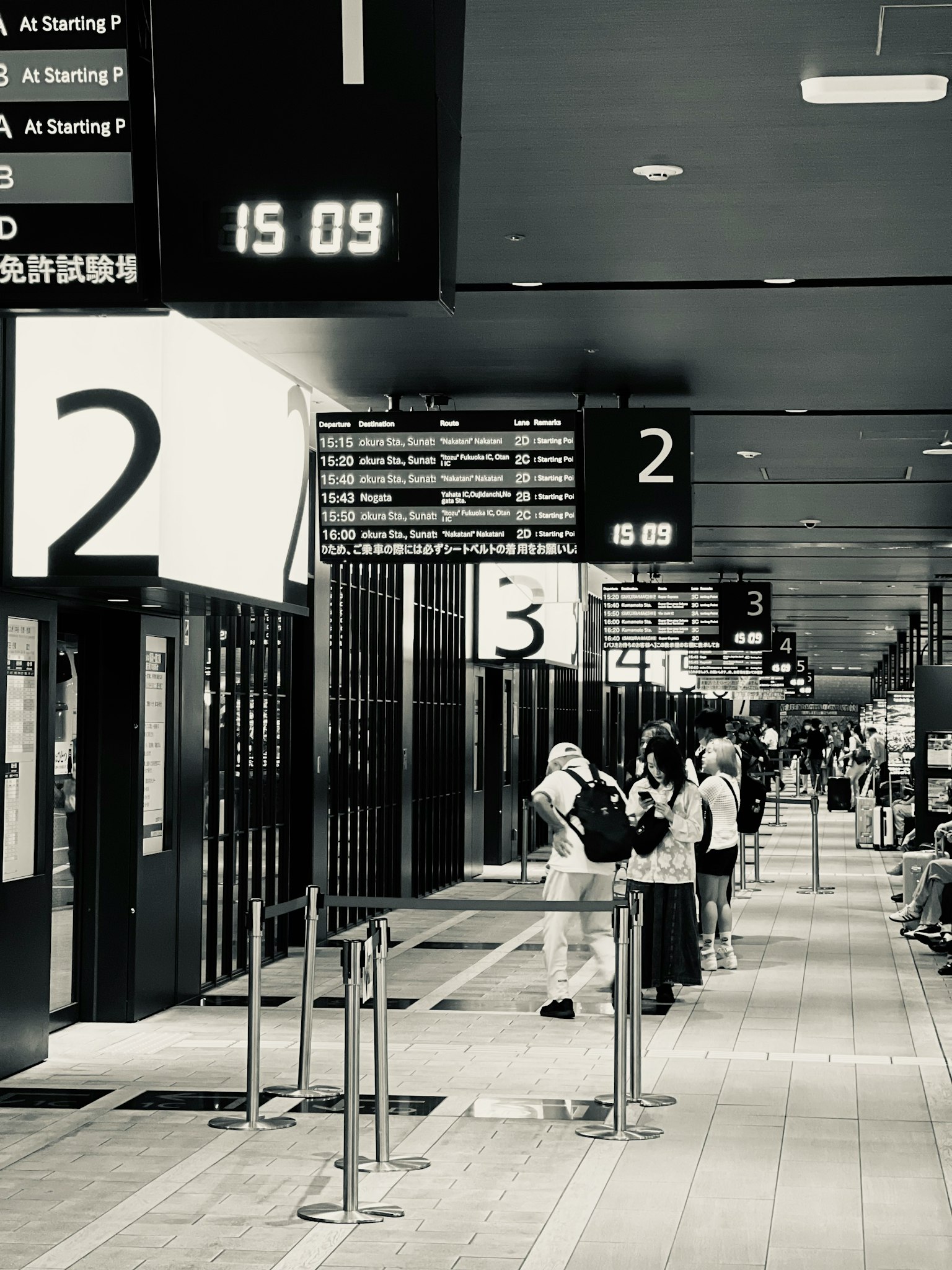 駅のプラットフォームに並ぶ乗客と表示板
