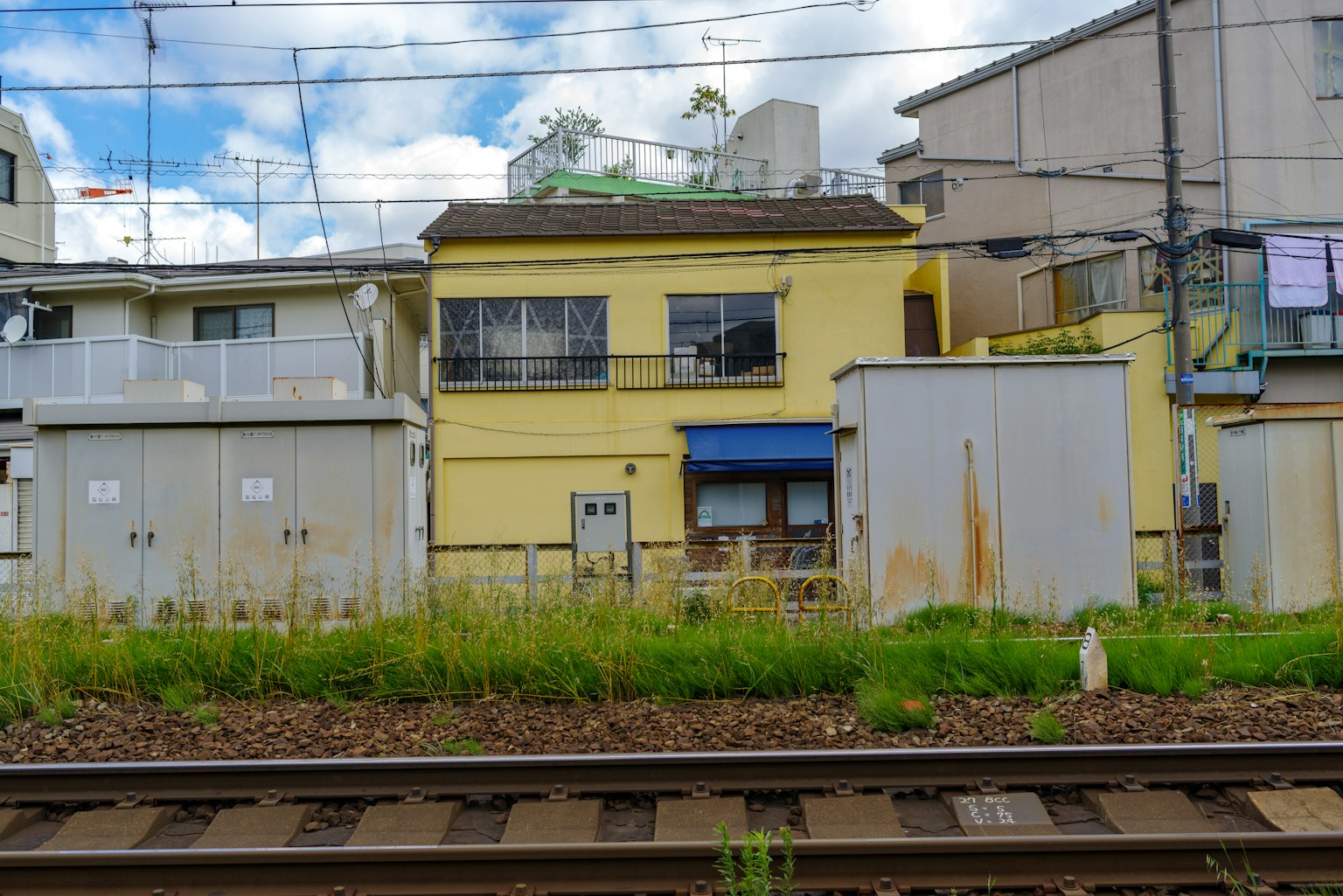 Casa gialla vicino ai binari del treno con edifici circostanti