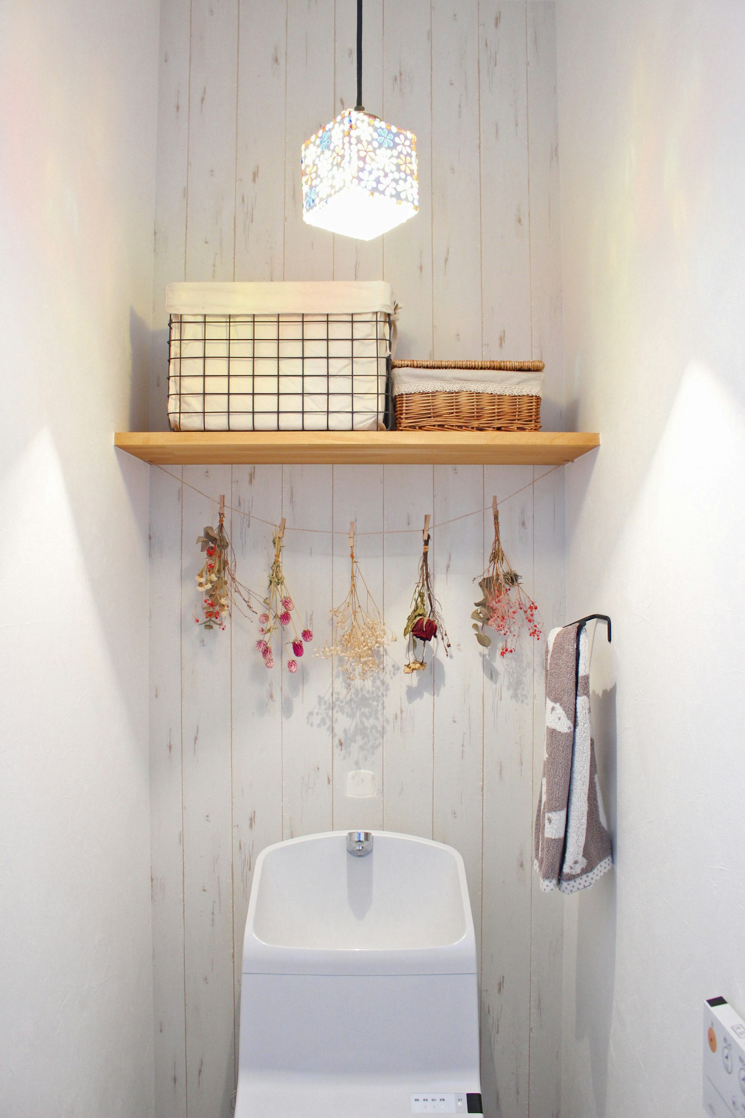 Interior de un baño con un inodoro blanco y una estantería de madera con elementos decorativos