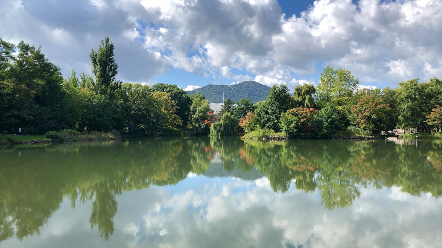 Ruhige Seenlandschaft mit blauem Himmel, der Bäume und Berge reflektiert