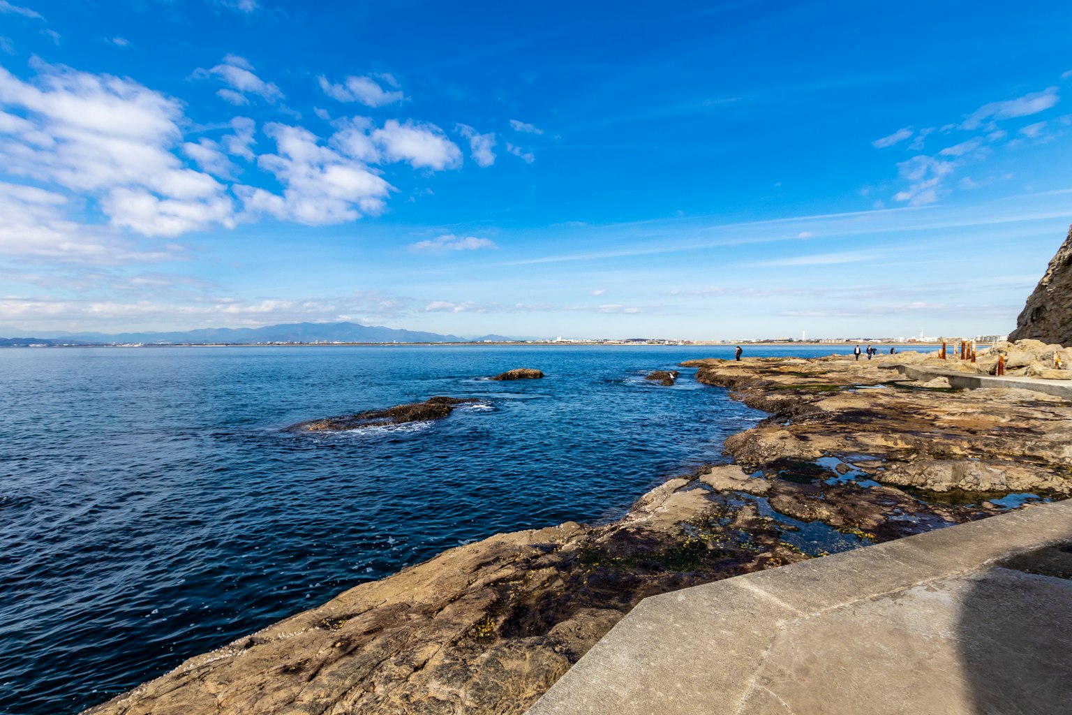 Pemandangan indah langit biru dan lautan garis pantai berbatu dengan pegunungan jauh