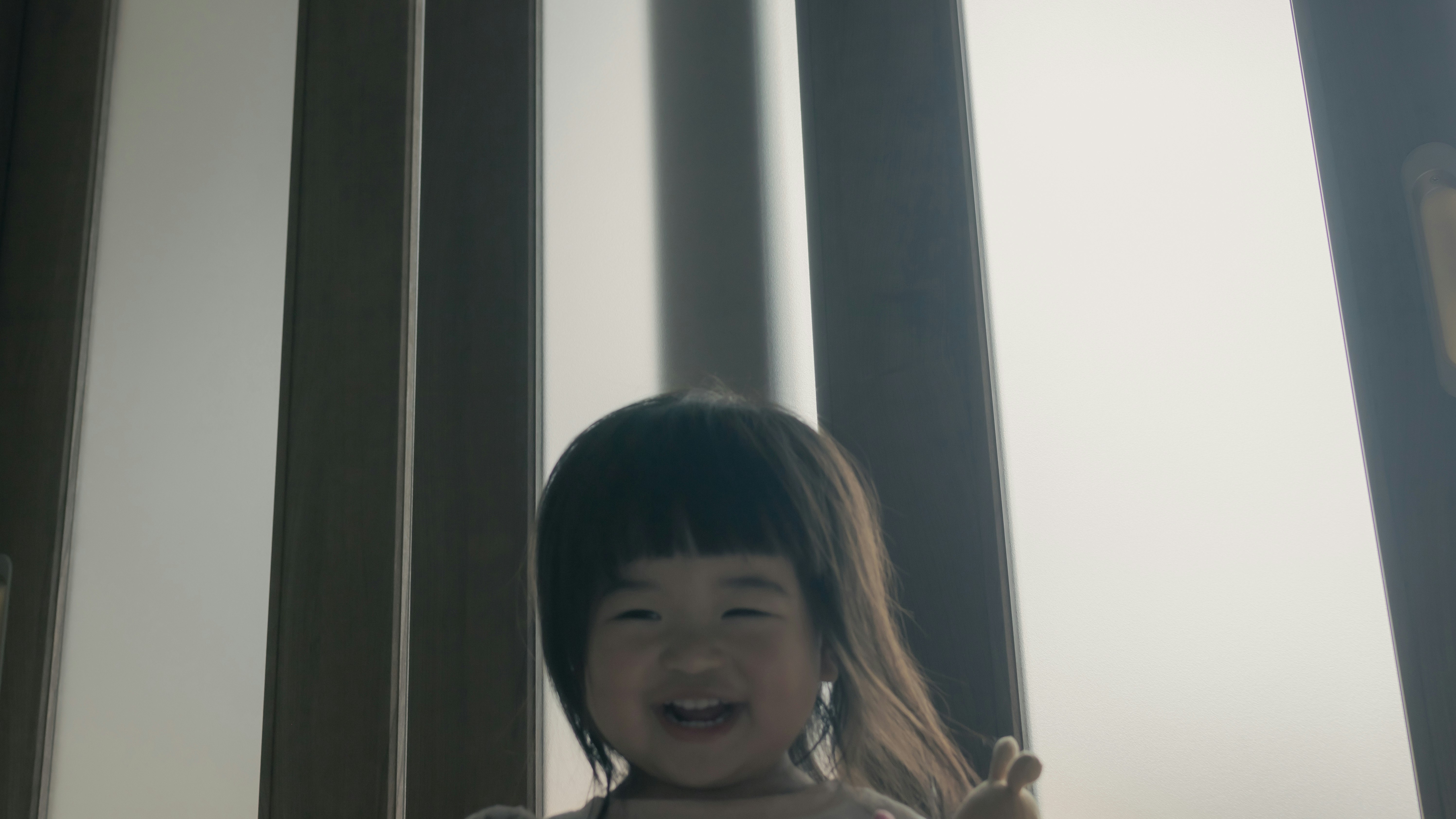 窓辺で笑うおかっぱ頭の子ども