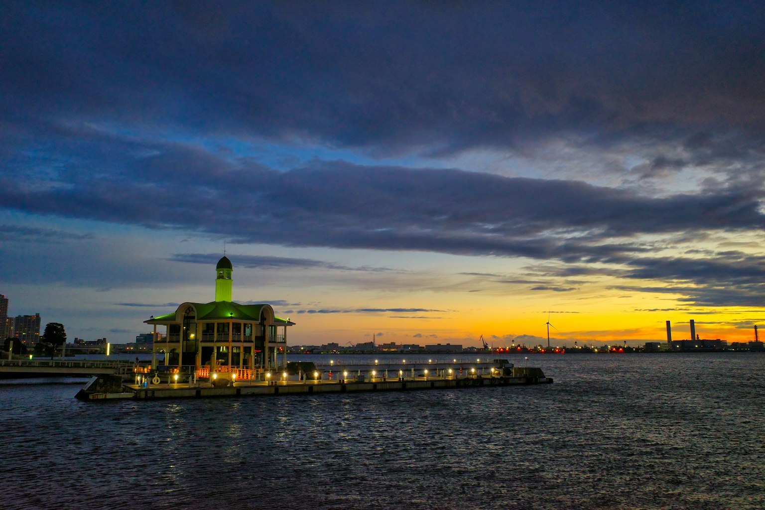 Building with a lighthouse illuminated at sunset over water
