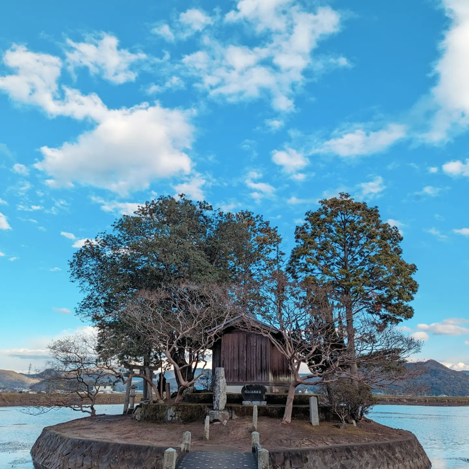 Una piccola baita su un'isola circondata da alberi sotto un cielo blu