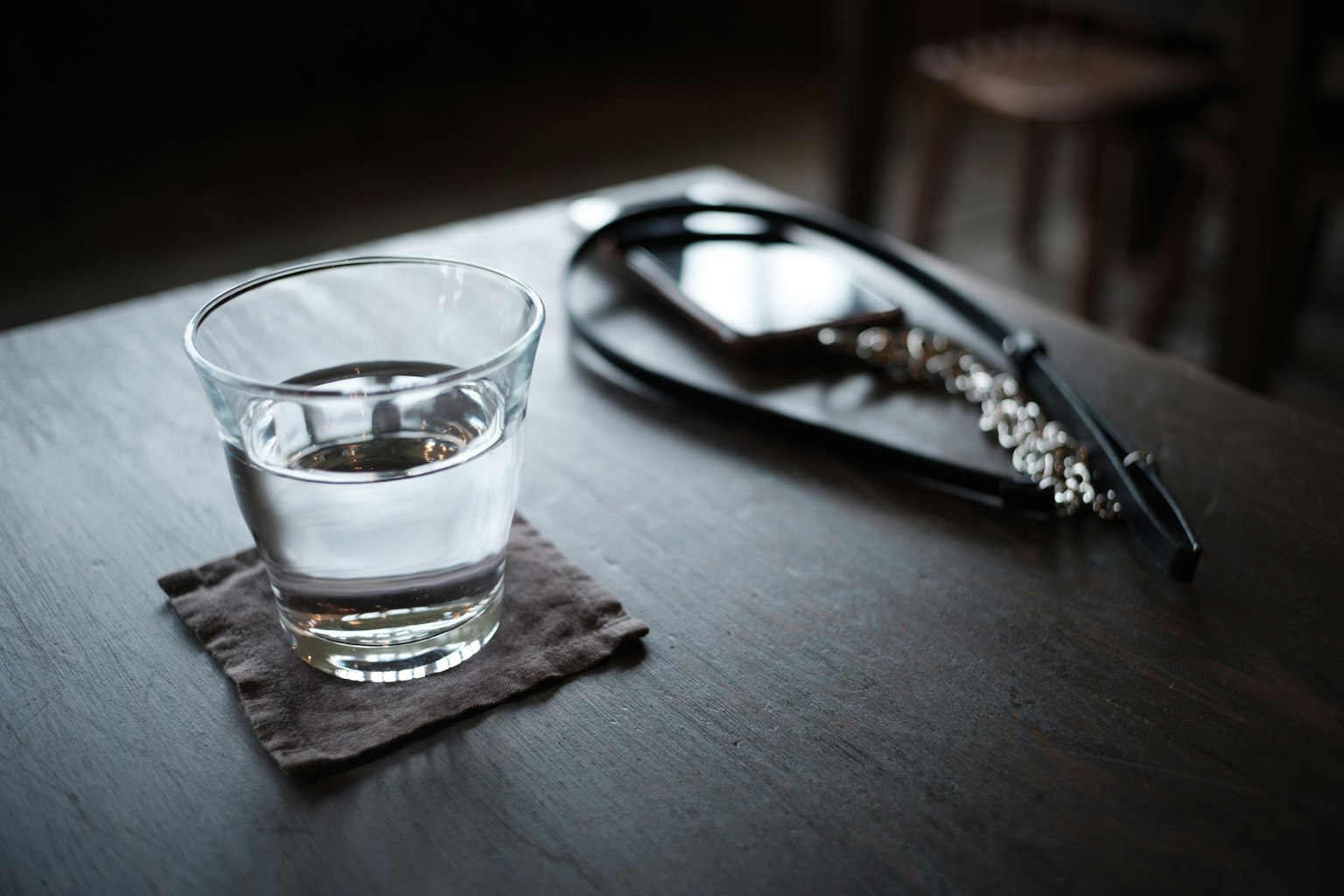 Un bicchiere d'acqua su un tavolo con cuffie nere accanto