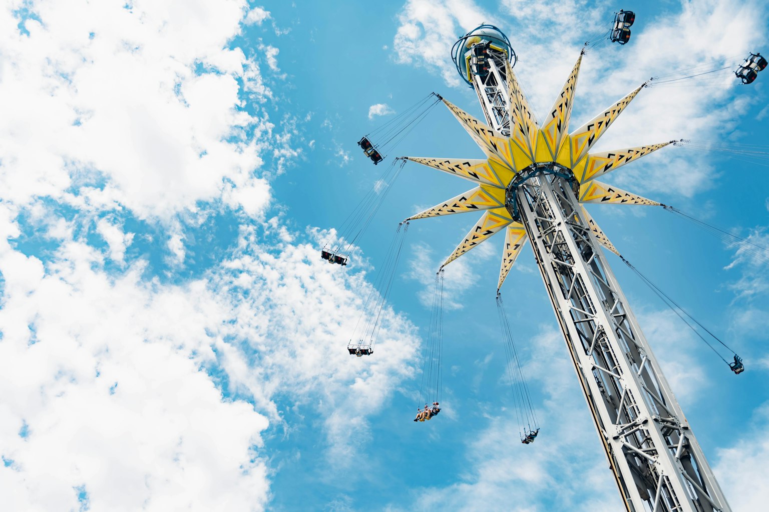Tall amusement park ride with a yellow star-shaped top against a blue sky