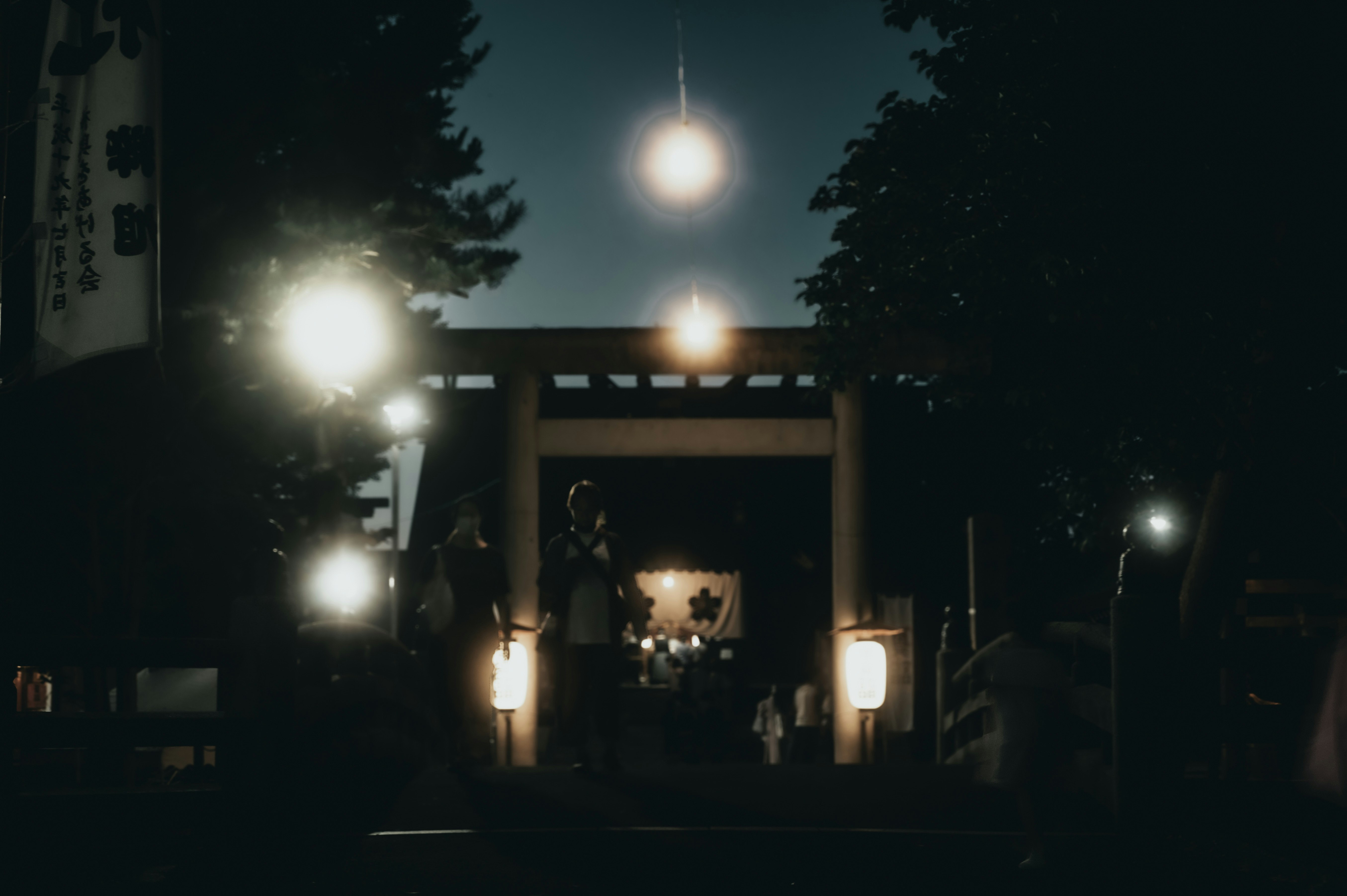 夜の神社参道で逆光に照らされる提灯と灯りの列