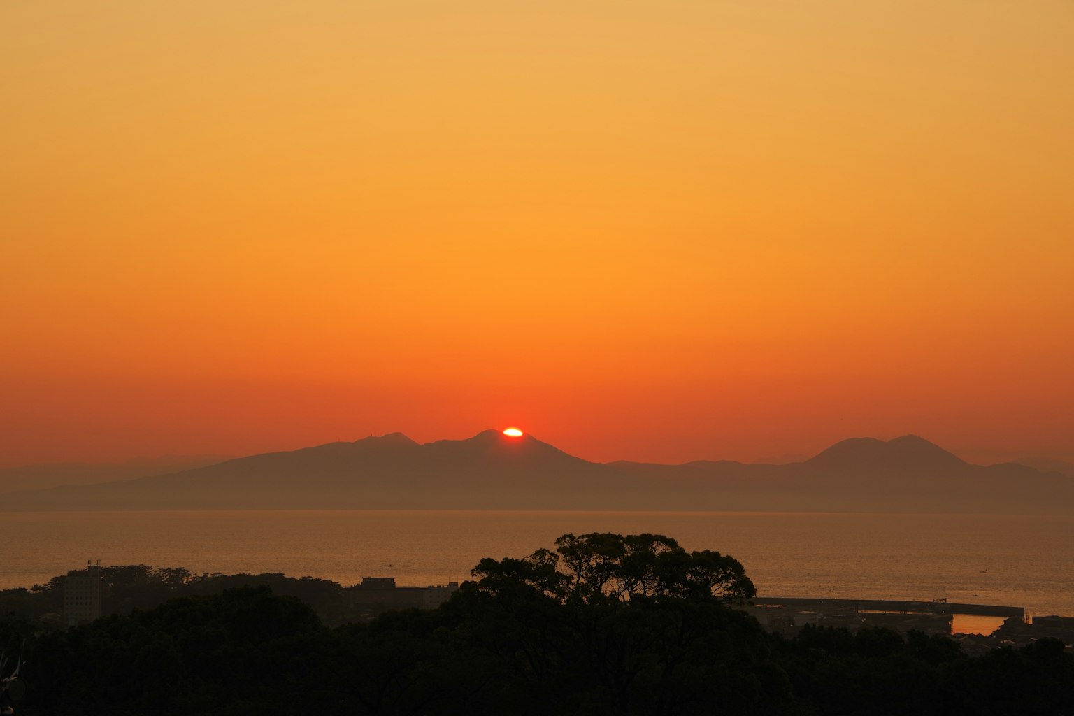 Coucher de soleil sur des montagnes avec silhouettes et ciel orange vif