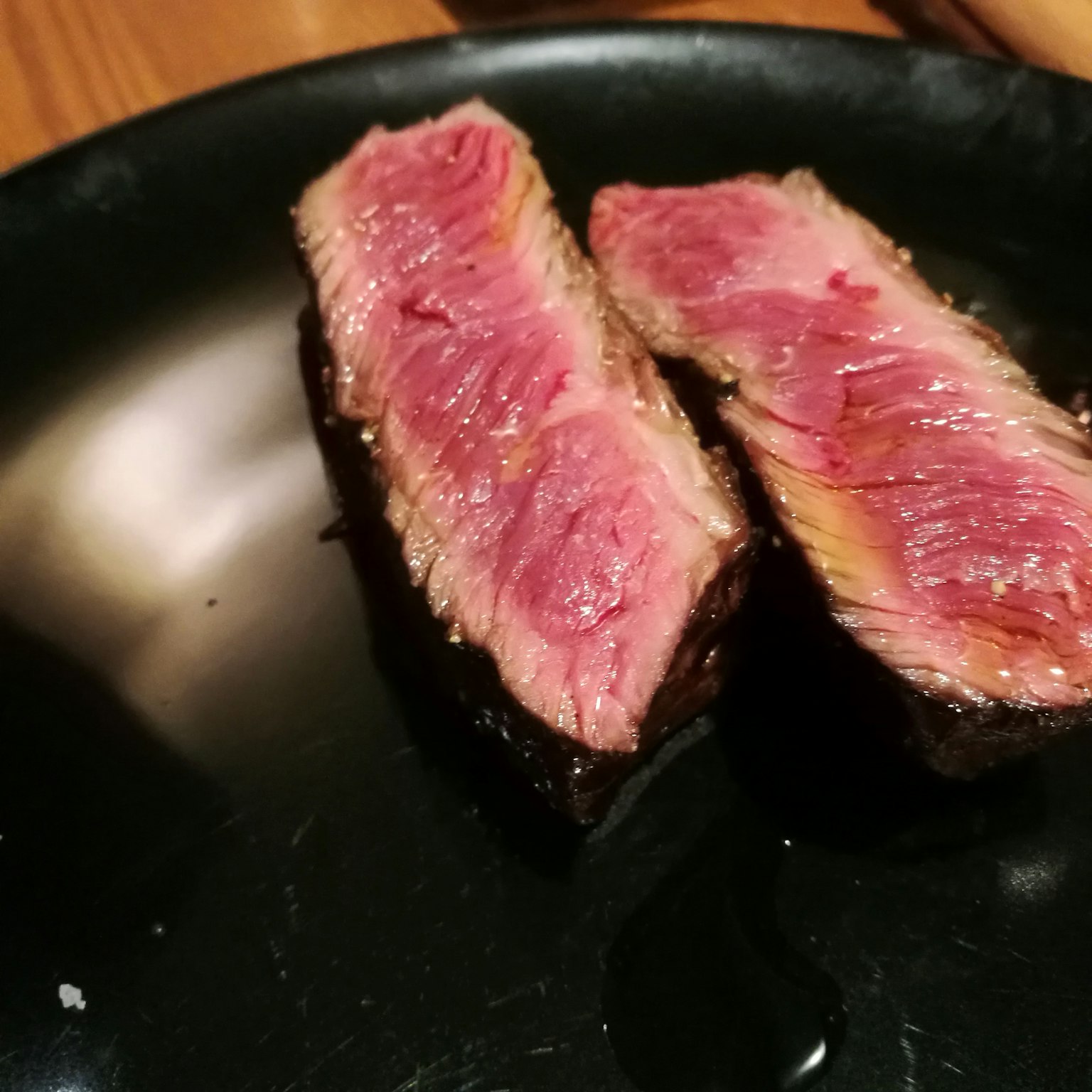 Deux tranches de steak montrant un intérieur rose sur une assiette noire