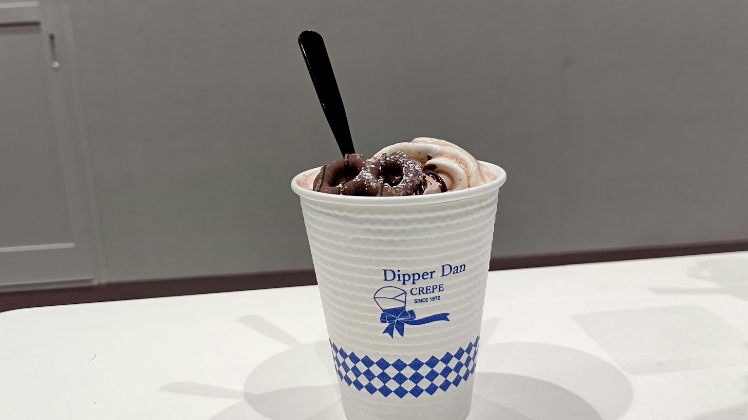Gelato al cioccolato in una tazza bianca con un cucchiaio nero
