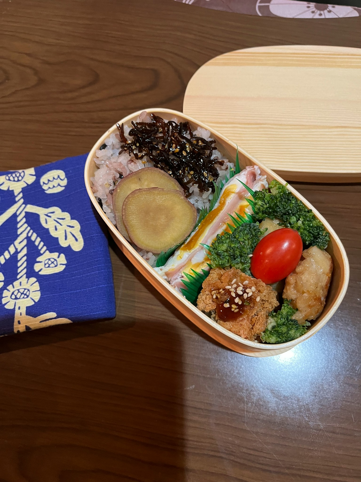 Hộp bento đầy màu sắc với nhiều món ăn và một mảnh vải xanh