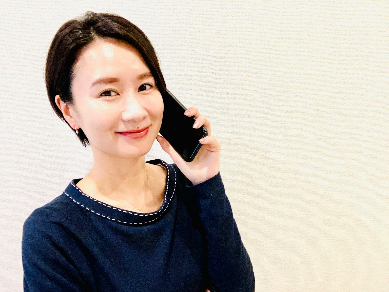 Seorang wanita tersenyum sambil memegang telepon