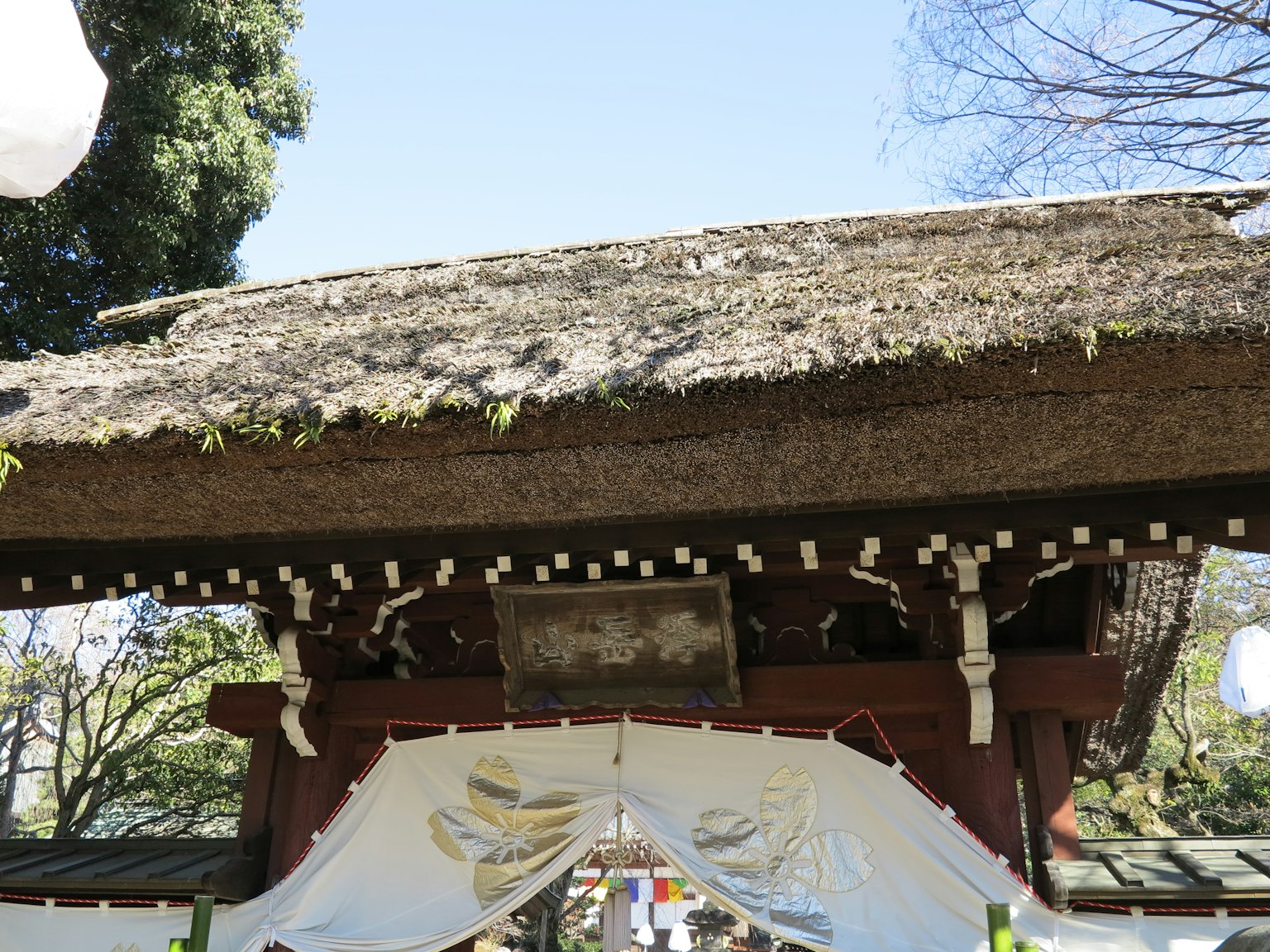 传统日本神社门，茅草屋顶，装饰性木雕和白色布帘