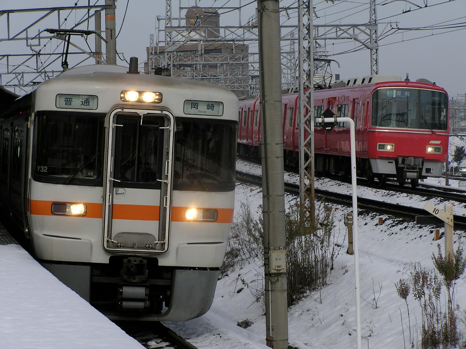 Eine Szene mit einem Zug, der im Schnee fährt, neben einem roten Zug