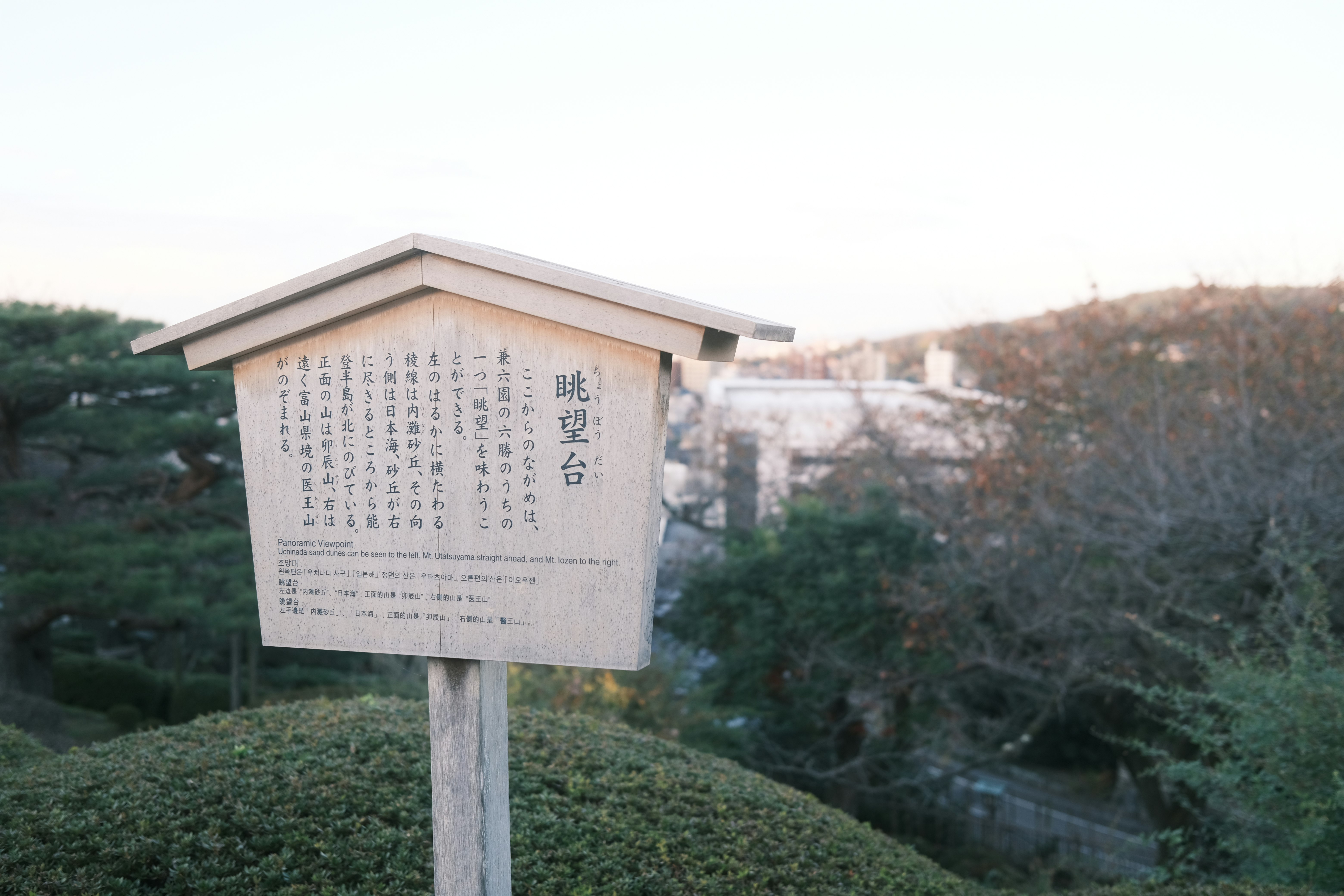 庭園の小さな案内板と石碑のある風景