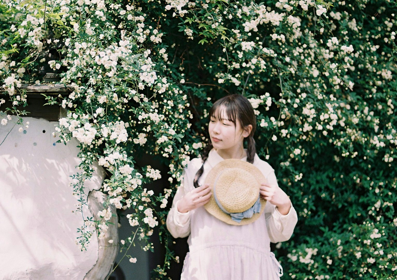 Girl holding straw hat surrounded by blooming flowers