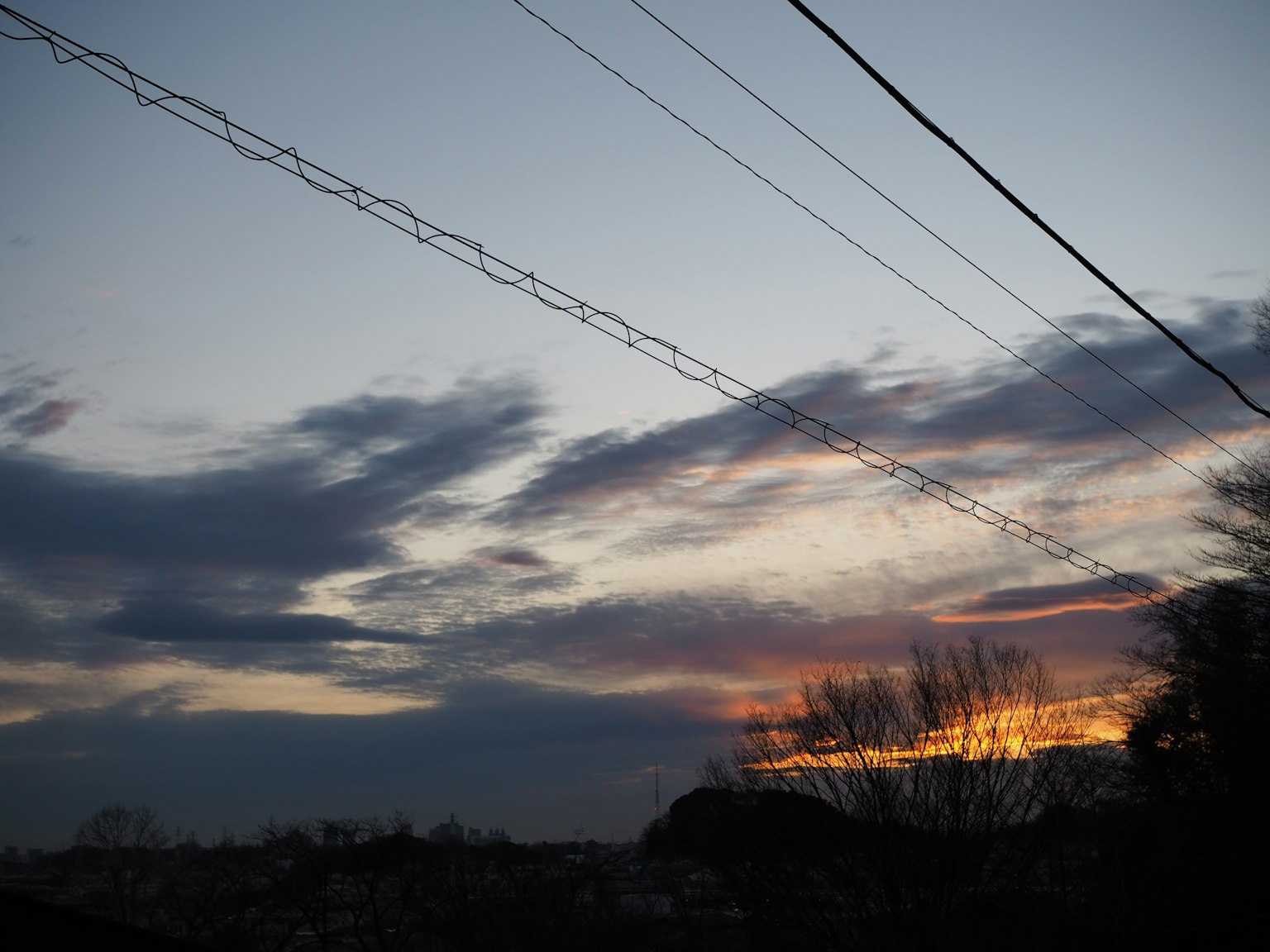 Ciel au coucher du soleil avec des nuages et des lignes électriques