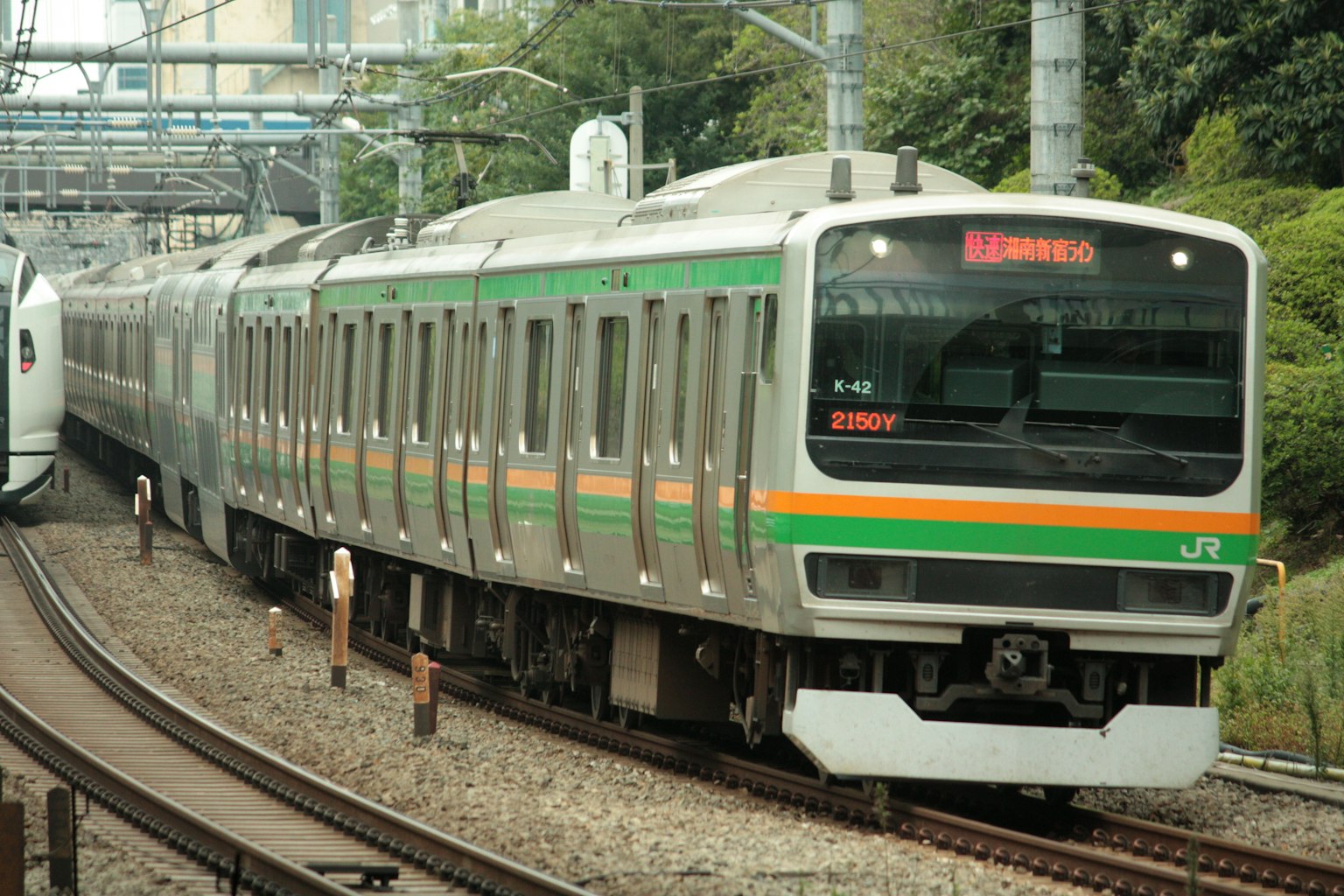 日本列车，绿色和橙色条纹在轨道上行驶
