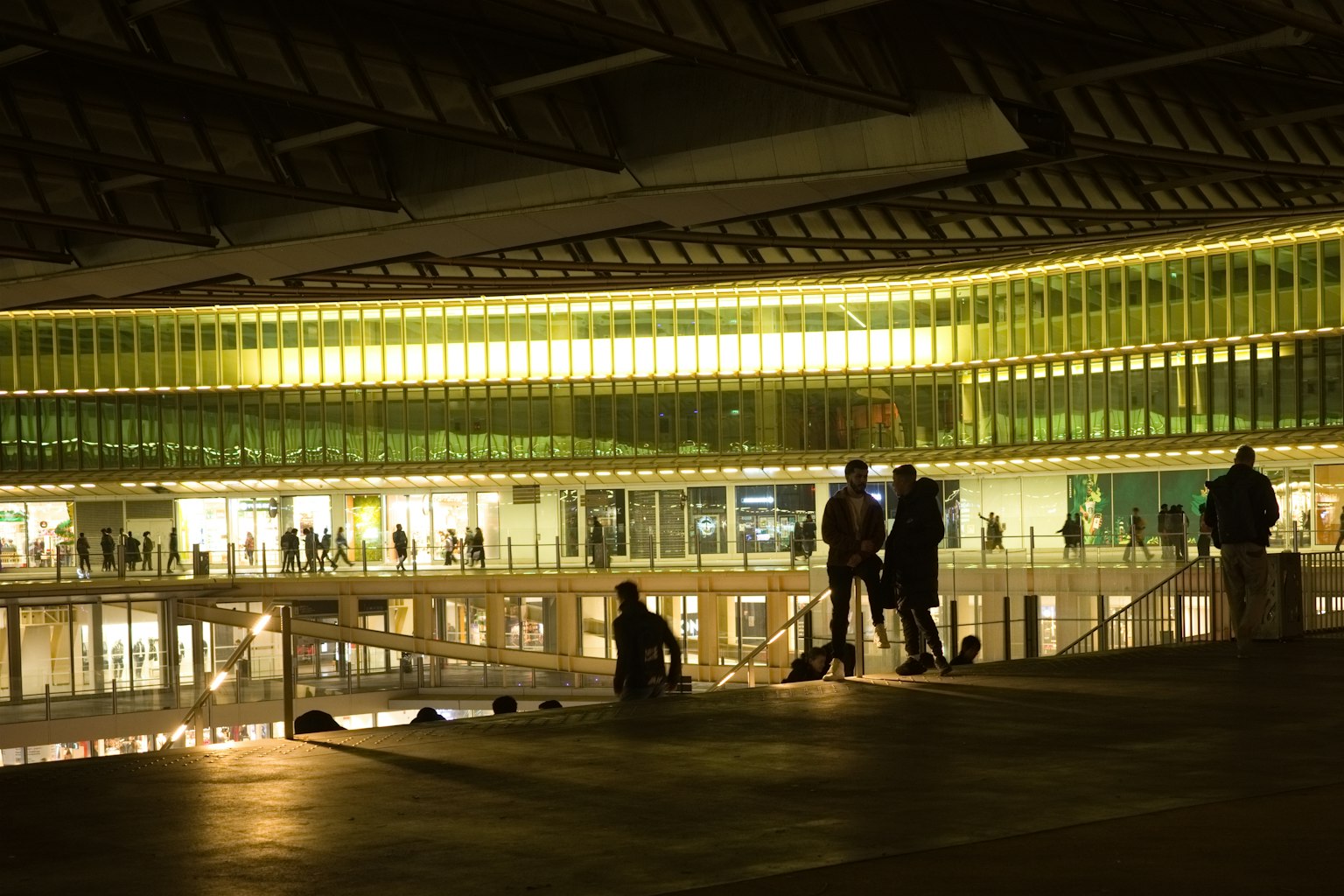 Interior de un edificio moderno iluminado por la noche con siluetas de personas