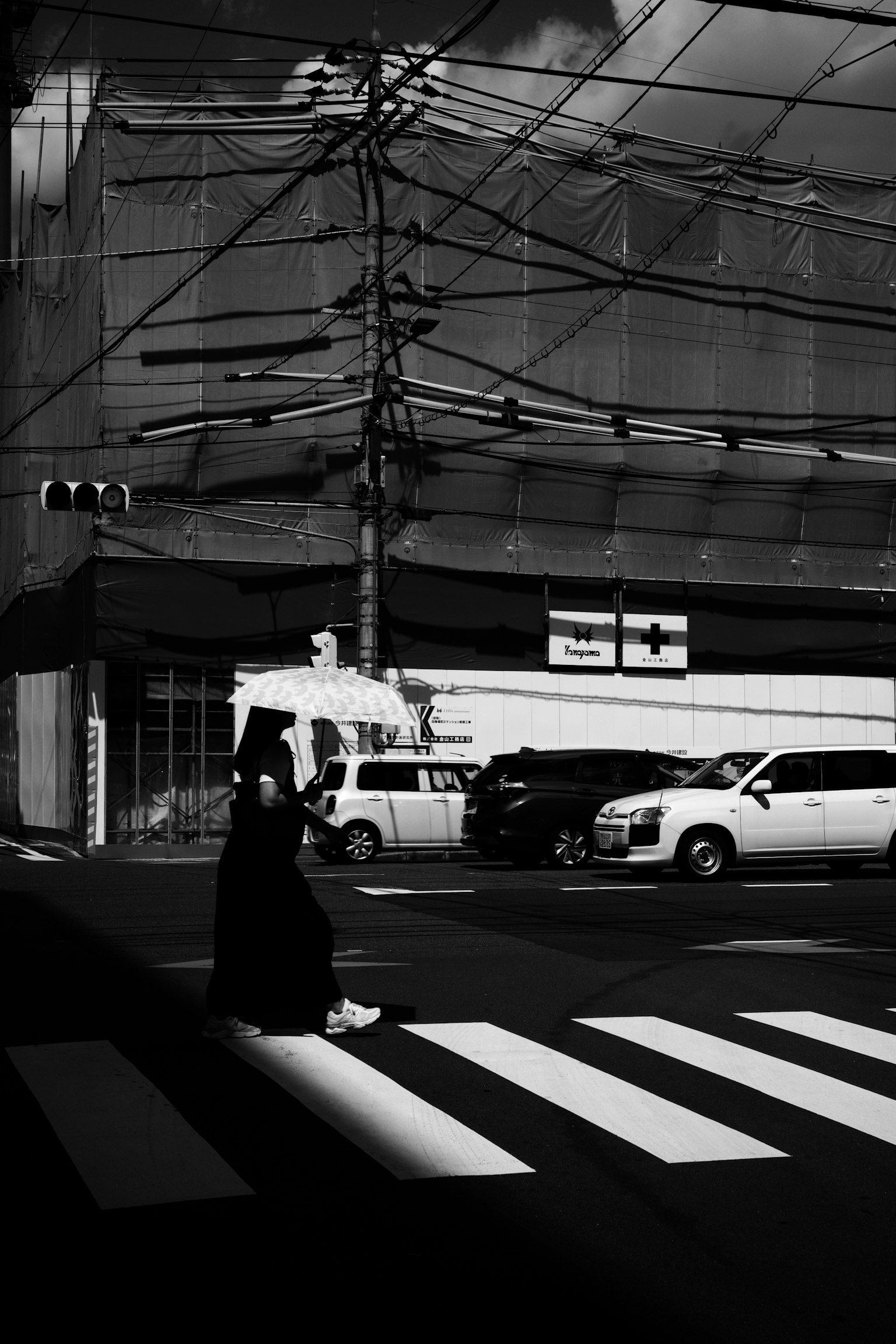 Una persona con un paraguas cruzando la calle en una intersección en blanco y negro