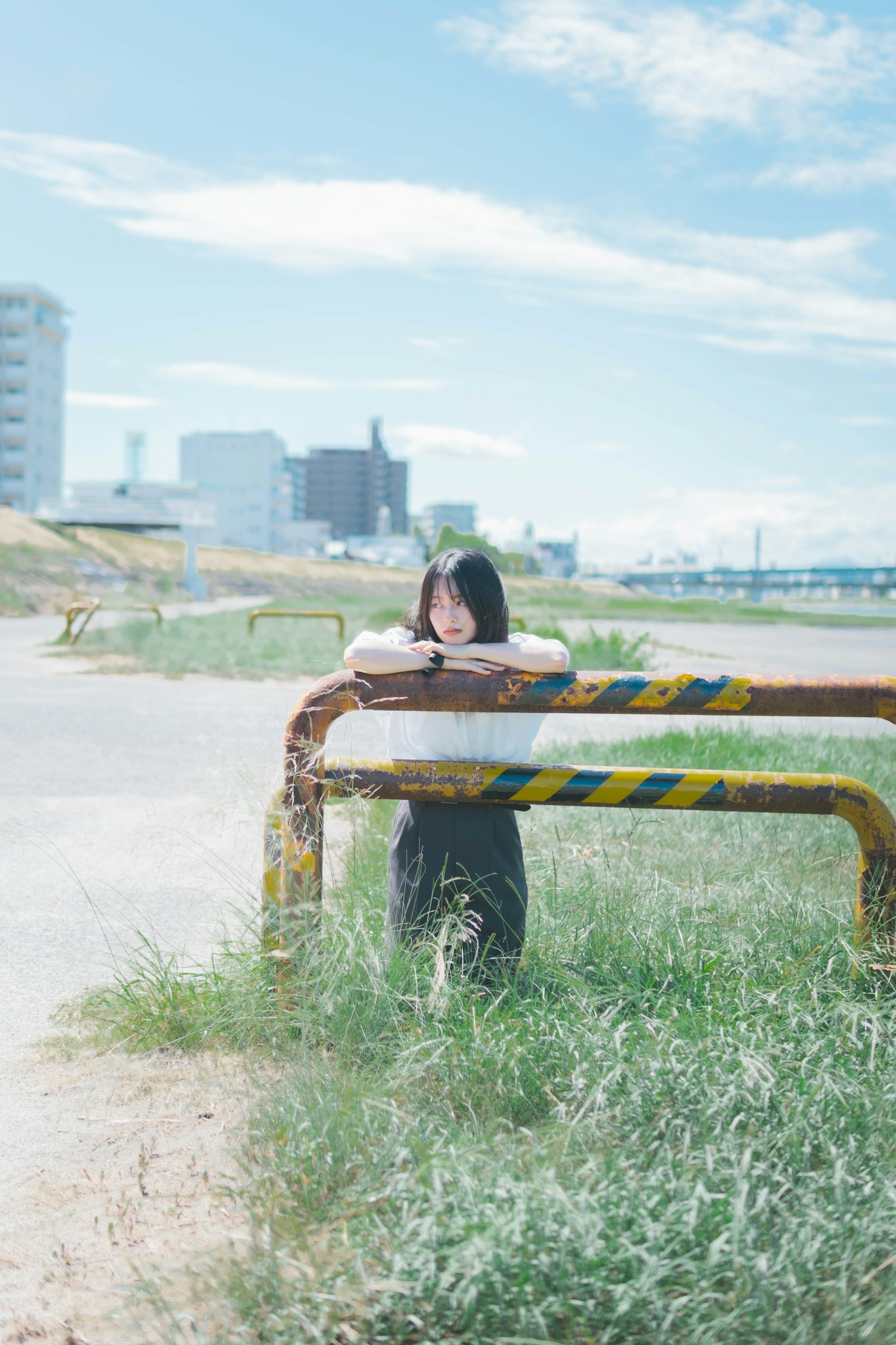 Fille s'appuyant sur une vieille barricade sous un ciel bleu avec un paysage urbain