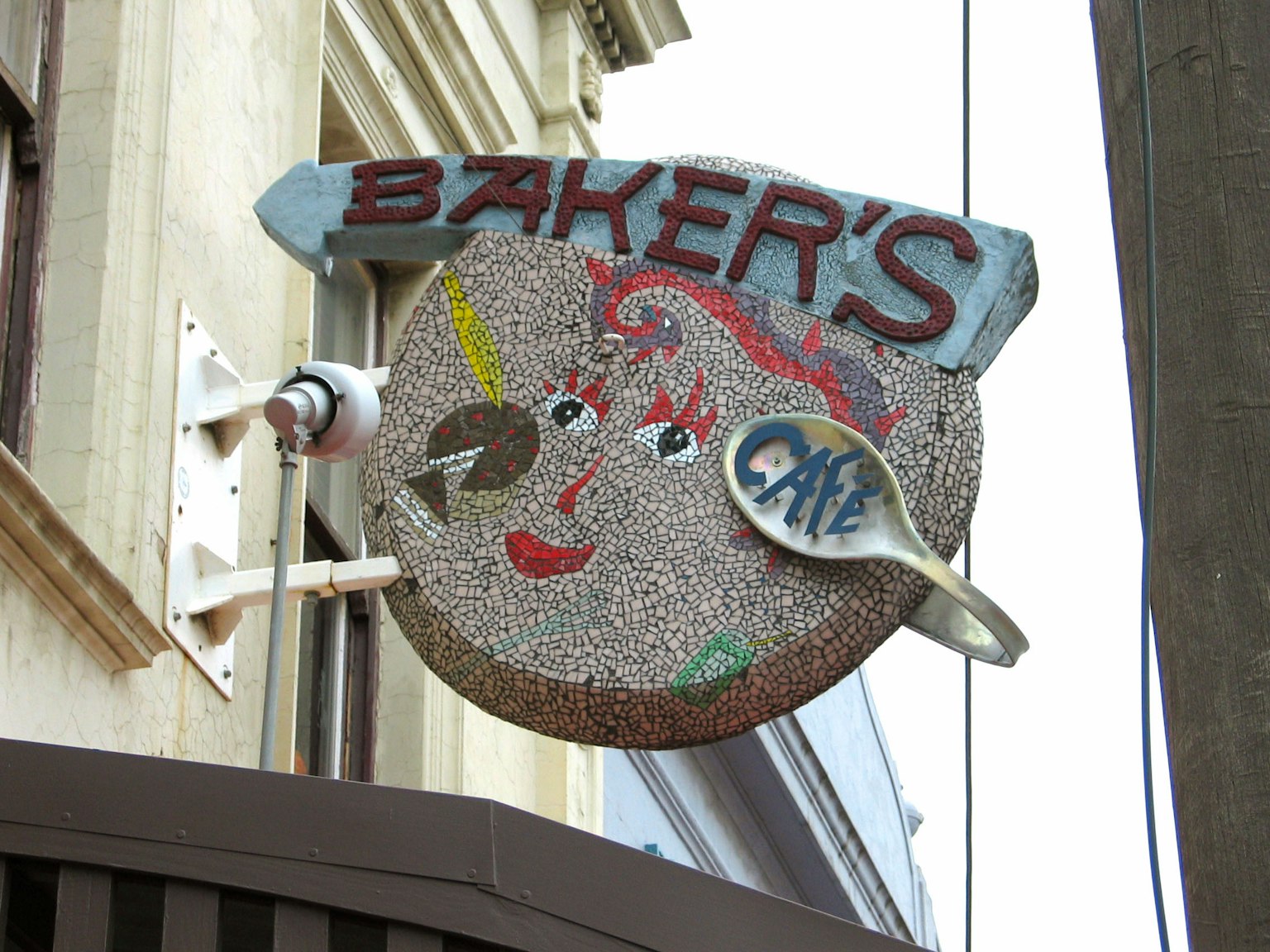 Das einzigartige Schild des Baker's Cafe zeigt ein farbenfrohes Mosaikdesign mit einem lächelnden Gesicht
