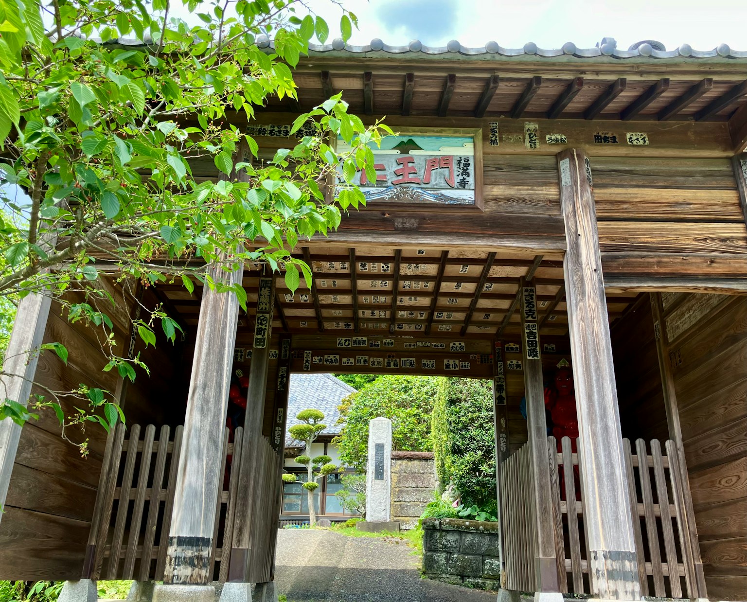 Wooden gate with green foliage and traditional Japanese architecture in the background