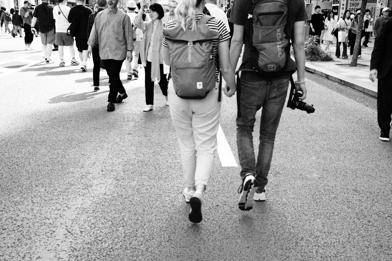 Pareja caminando en una calle de la ciudad en blanco y negro desde atrás