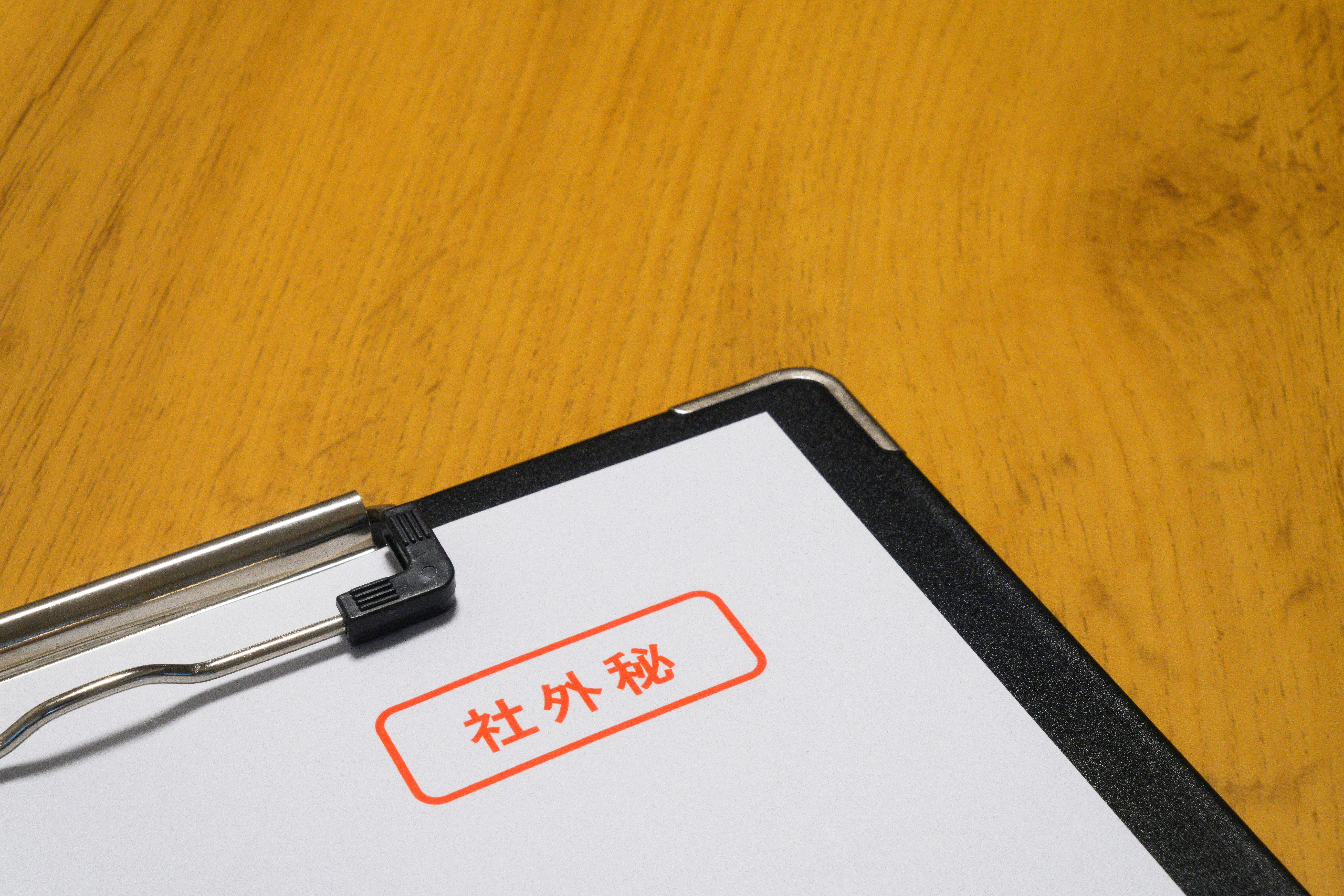 木桌上的夾板 白紙上有紅色框的文字