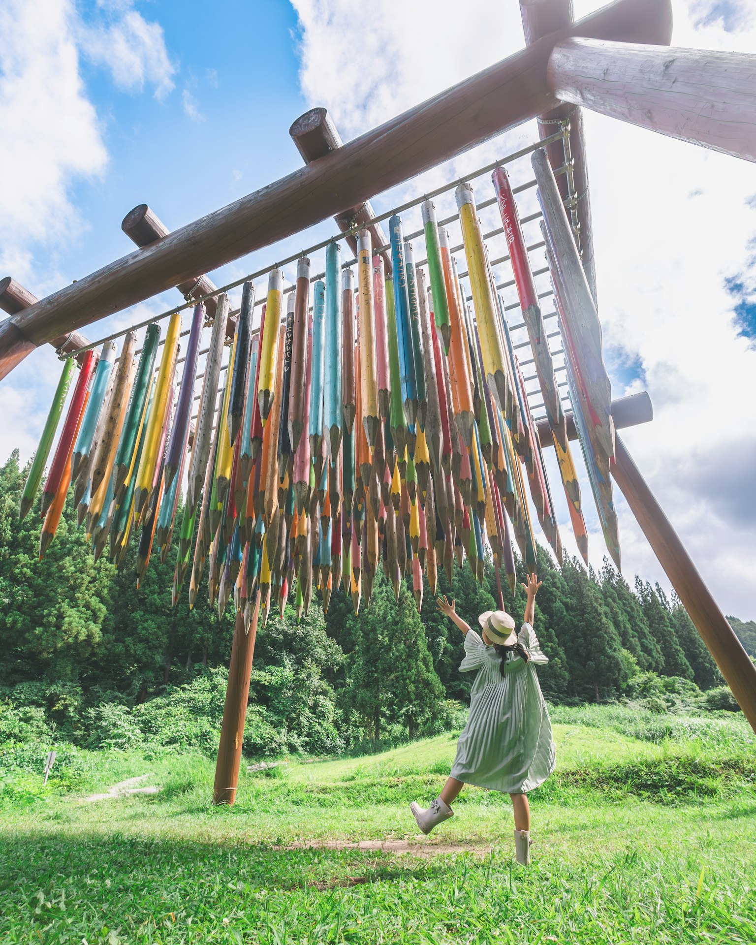 A woman enjoying a colorful pencil art installation in a lush green landscape