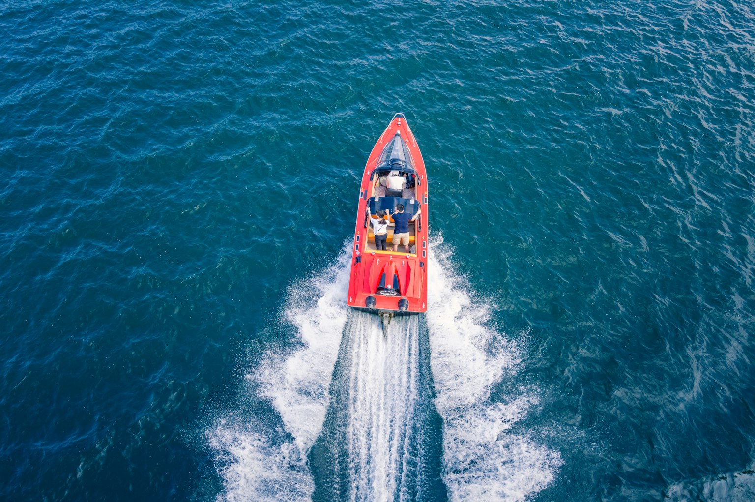 Rotes Boot, das durch blaues Wasser aus der Vogelperspektive fährt